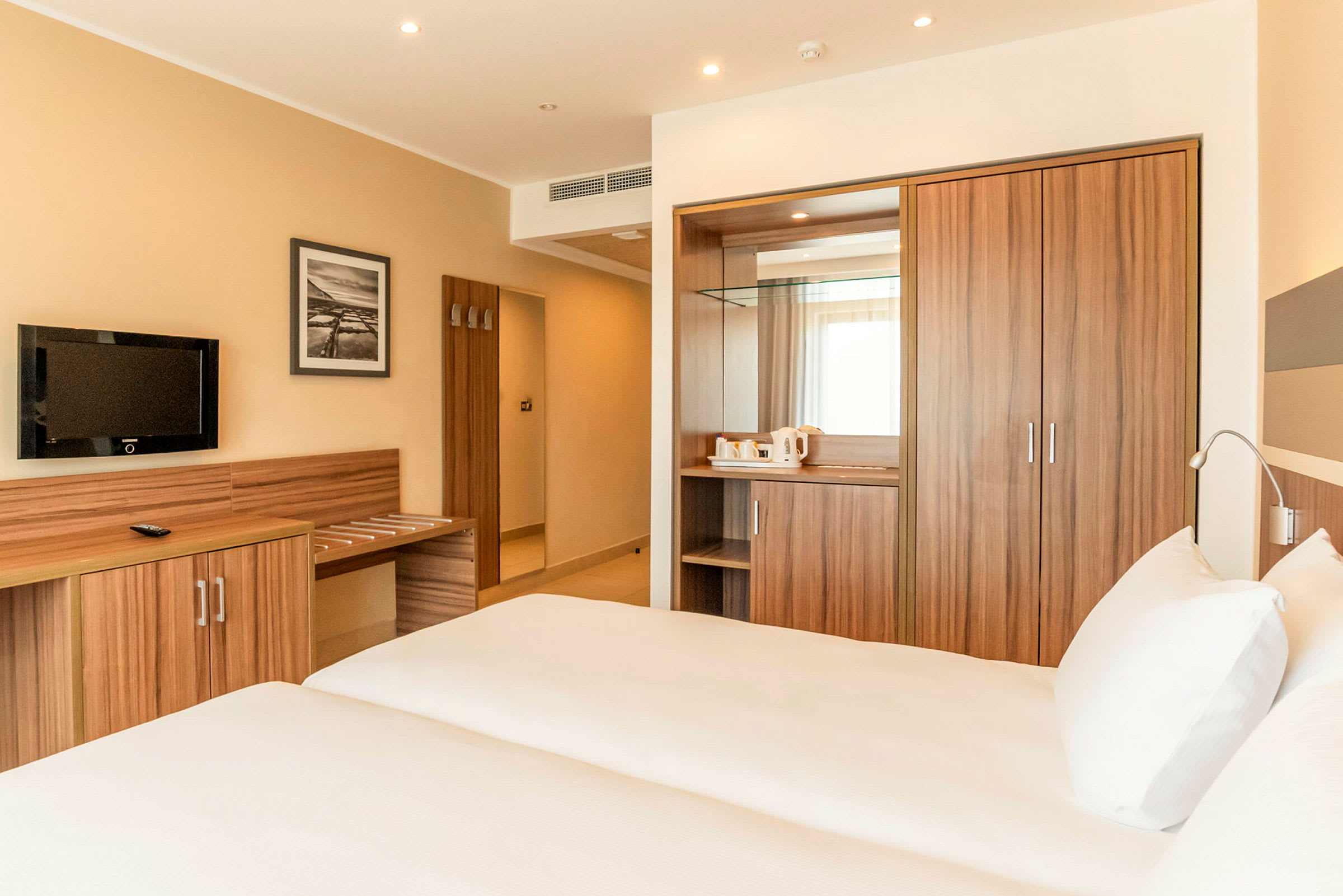 Ett hotellrum med två sängar, ett träskrivbord, och en garderob. (AI-genererad text)