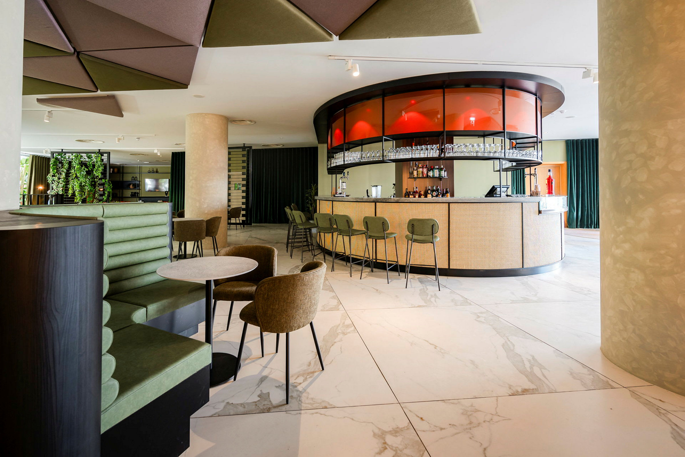 Interiör av en modern bar med en rund bardisk och stolar, omgivande sittplatser och dekorativa detaljer. (AI-genererad text)