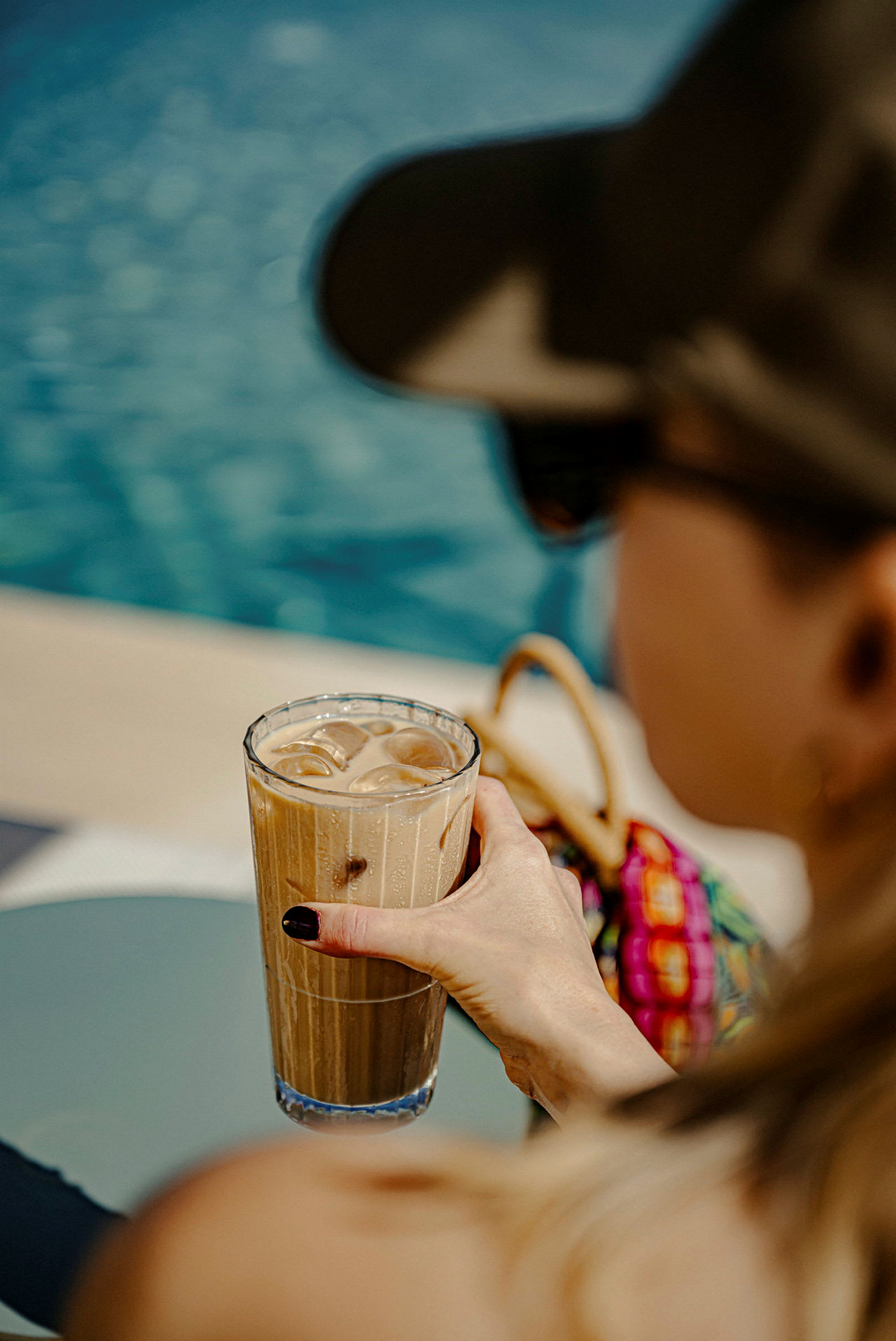 Ett glas iskaffe hålls vid en pool. (AI-genererad text)