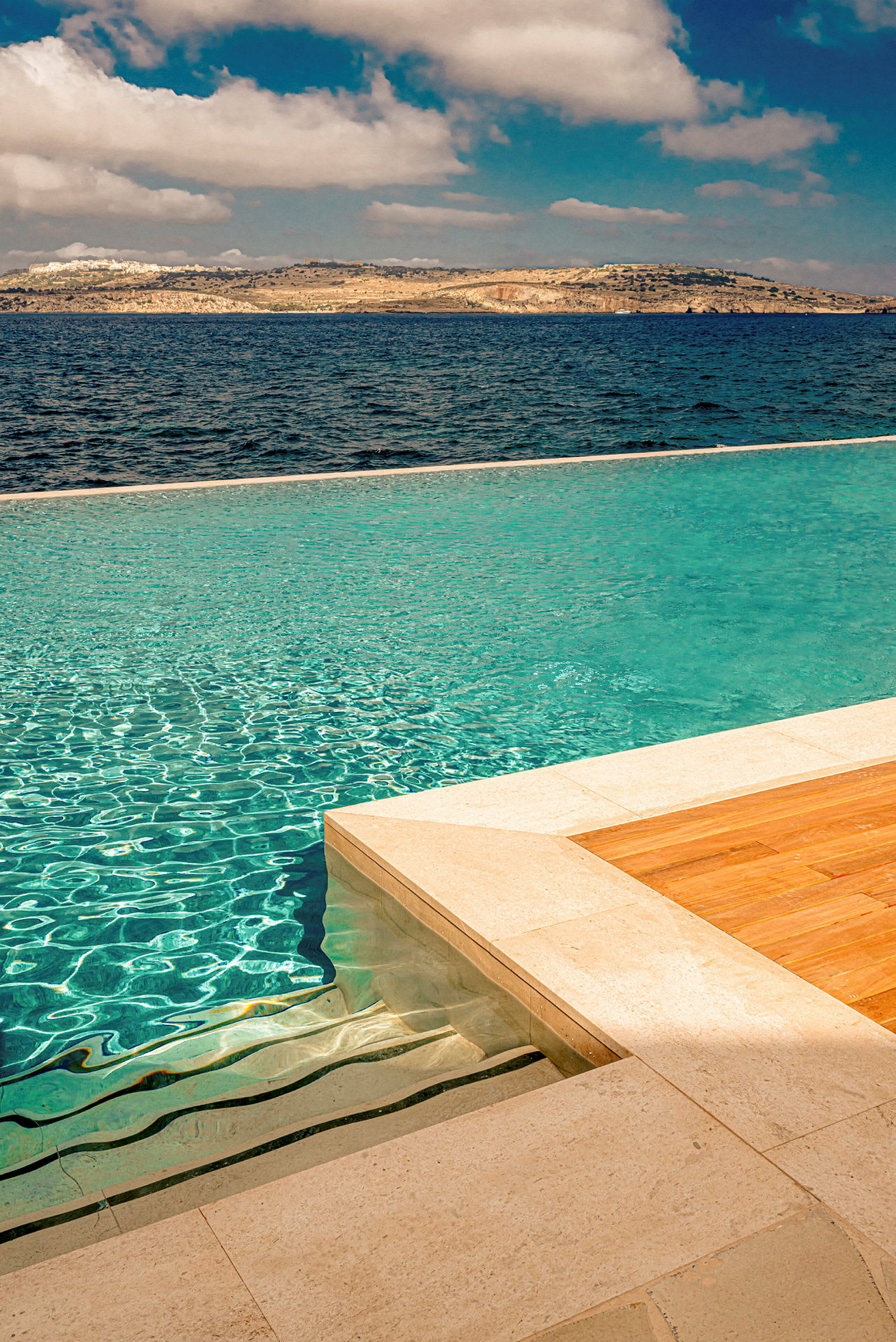 Infinitypool med utsikt över havet och en bergig kust. (AI-genererad text)