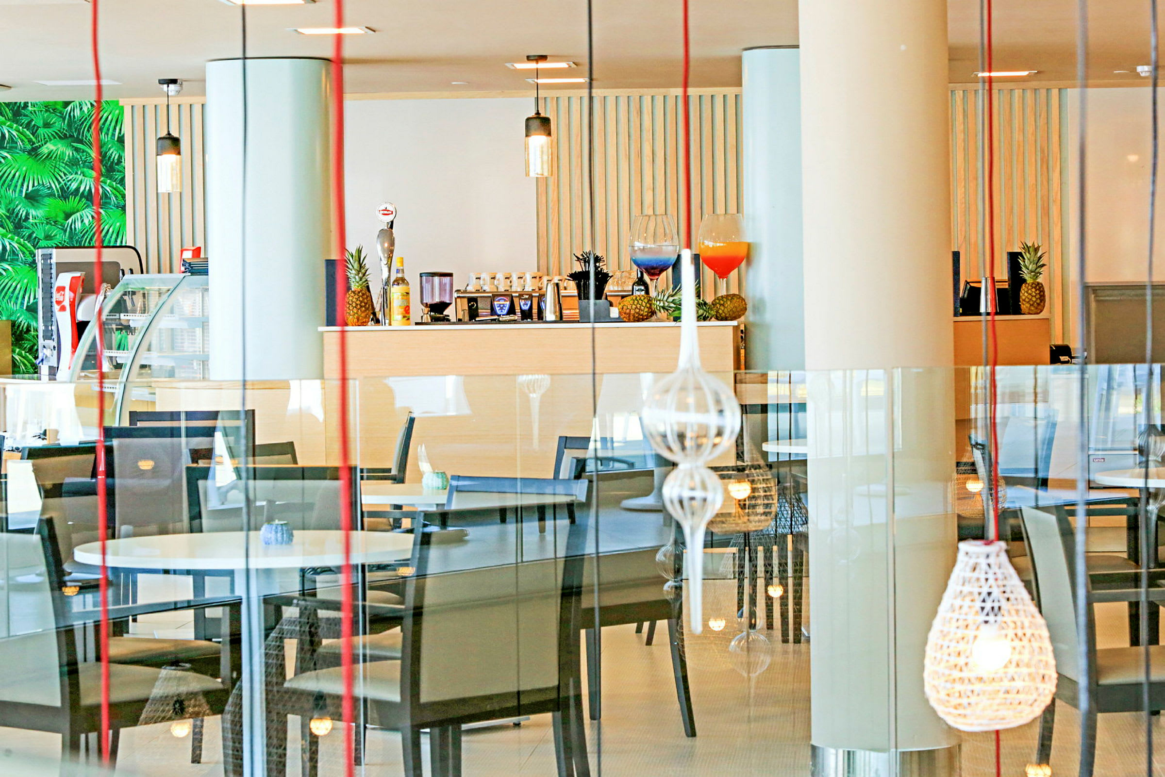 Inne i en restaurang med bord, stolar och dekorativa lampor. (AI-genererad text)