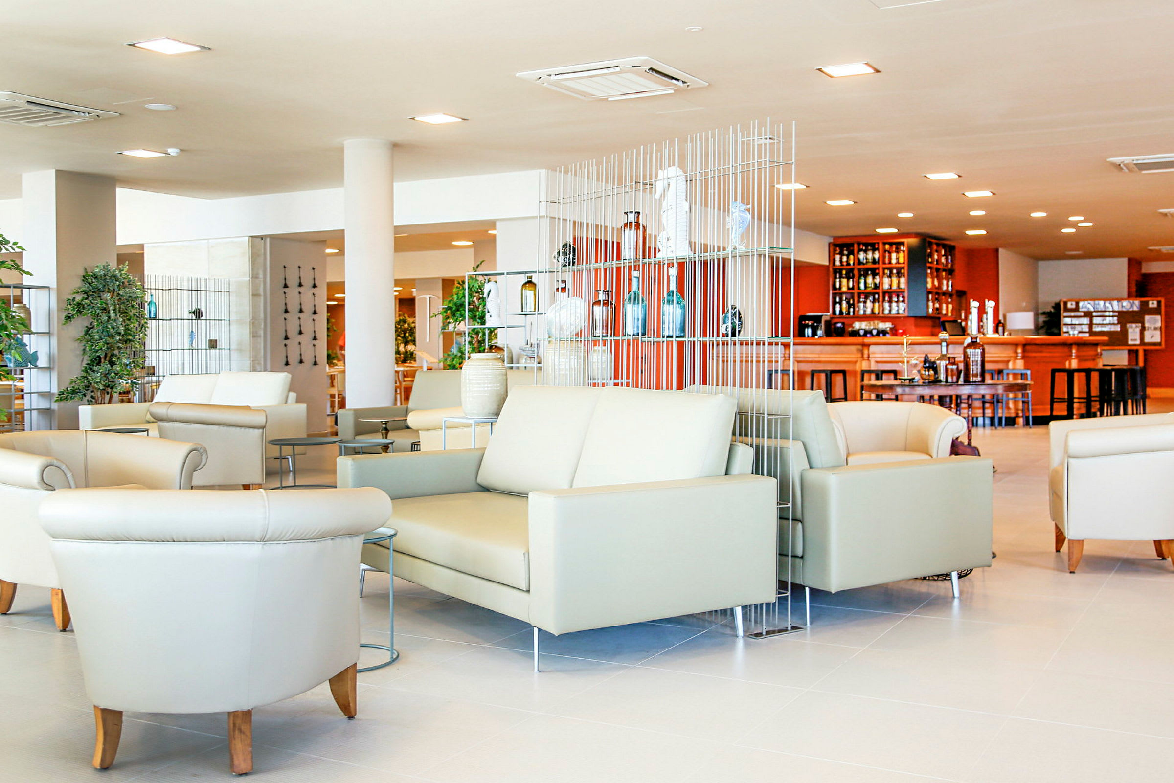 Ljus och modern lounge med soffor och fåtöljer samt en bar i bakgrunden. (AI-genererad text)