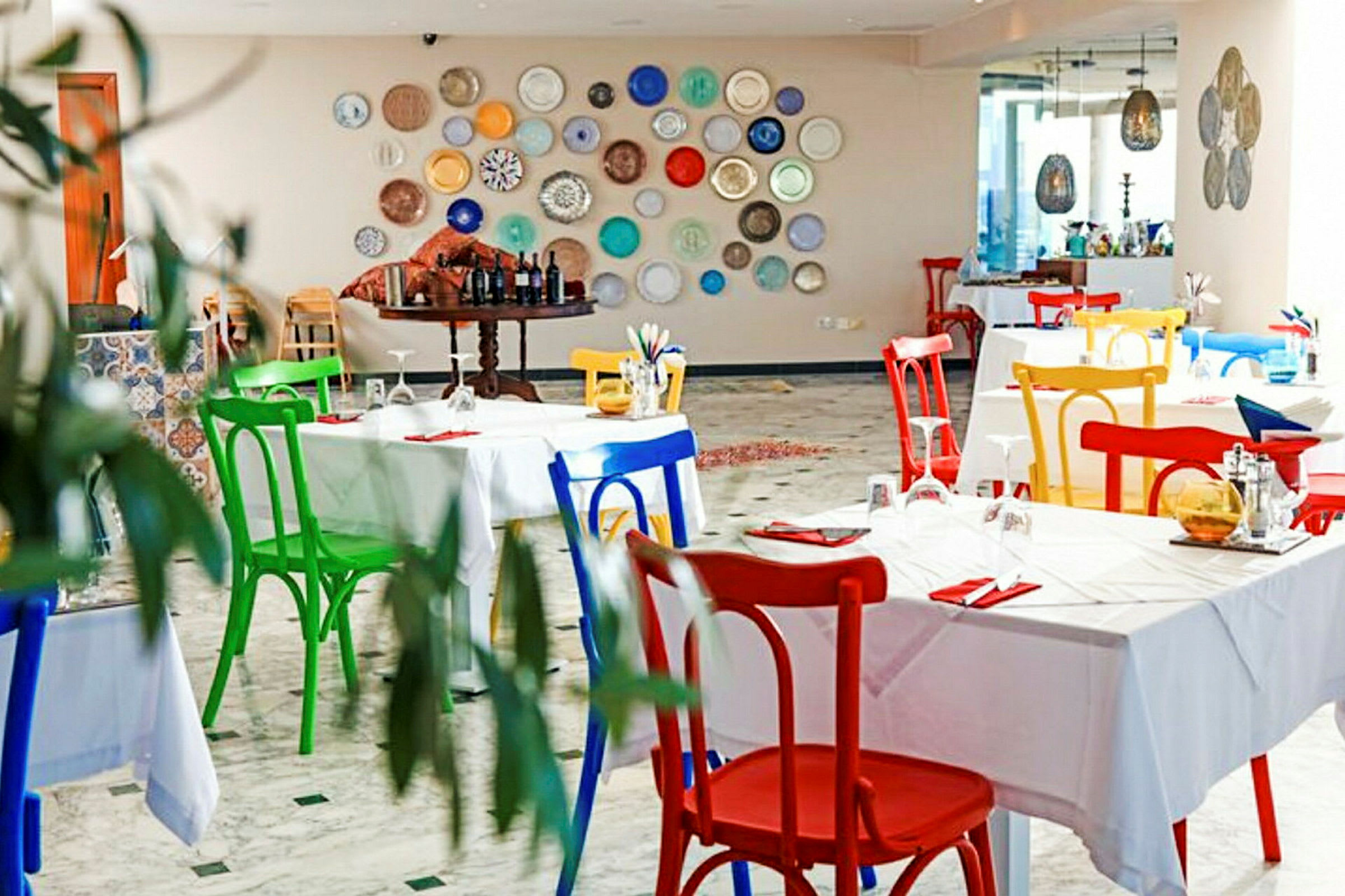 En restaurang med färgglada stolar och prydnadstallrikar på väggen. (AI-genererad text)