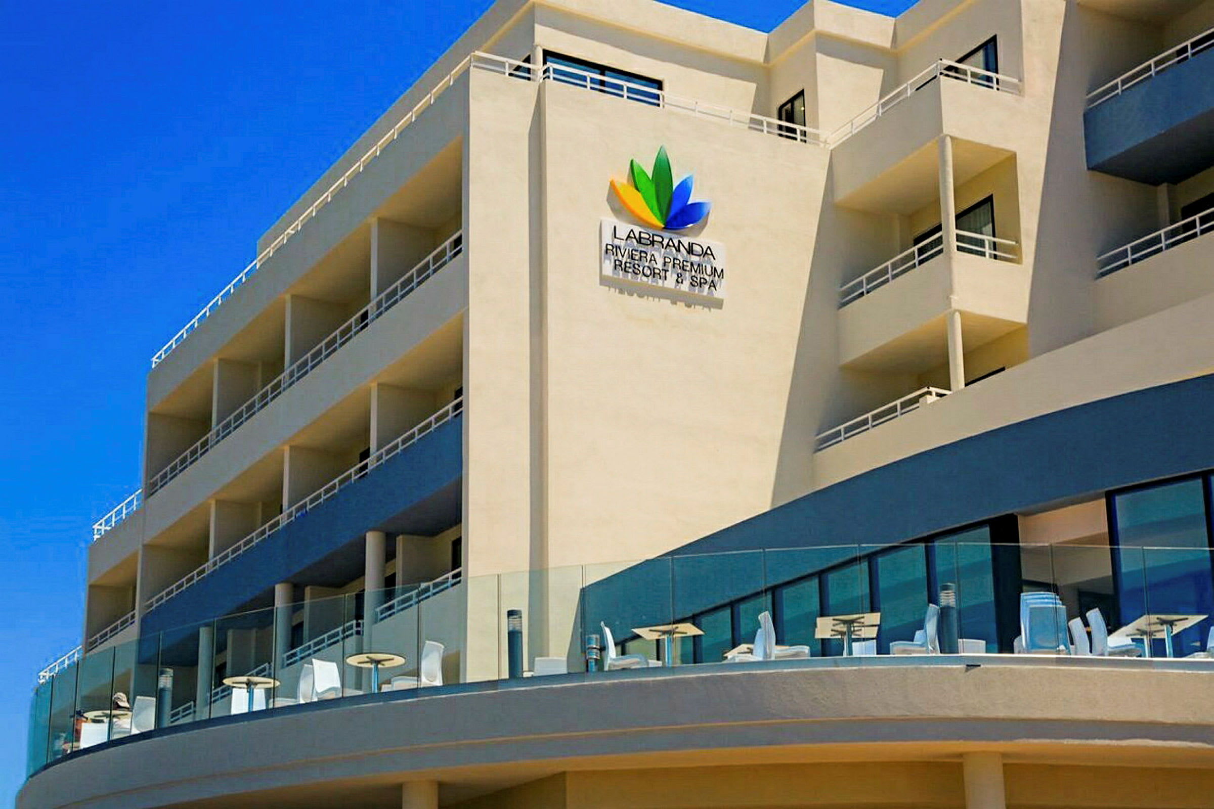 Exteriör av ett hotell med balkonger och uteservering. (AI-genererad text)