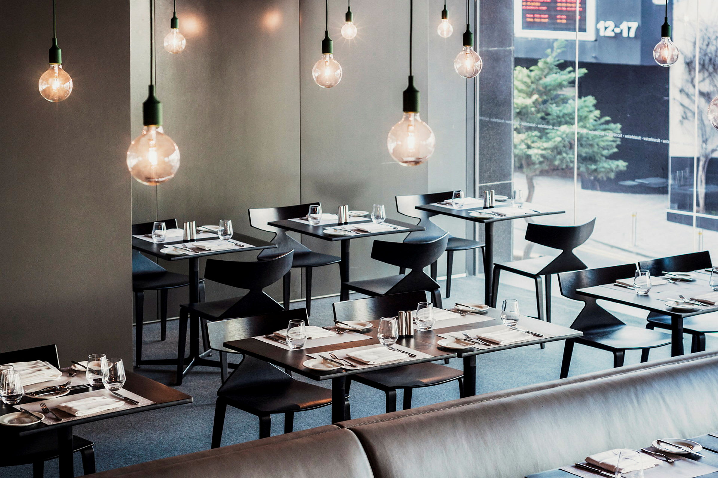 En modern restaurang med elegant dukade bord och hängande glödlampor. (AI-genererad text)
