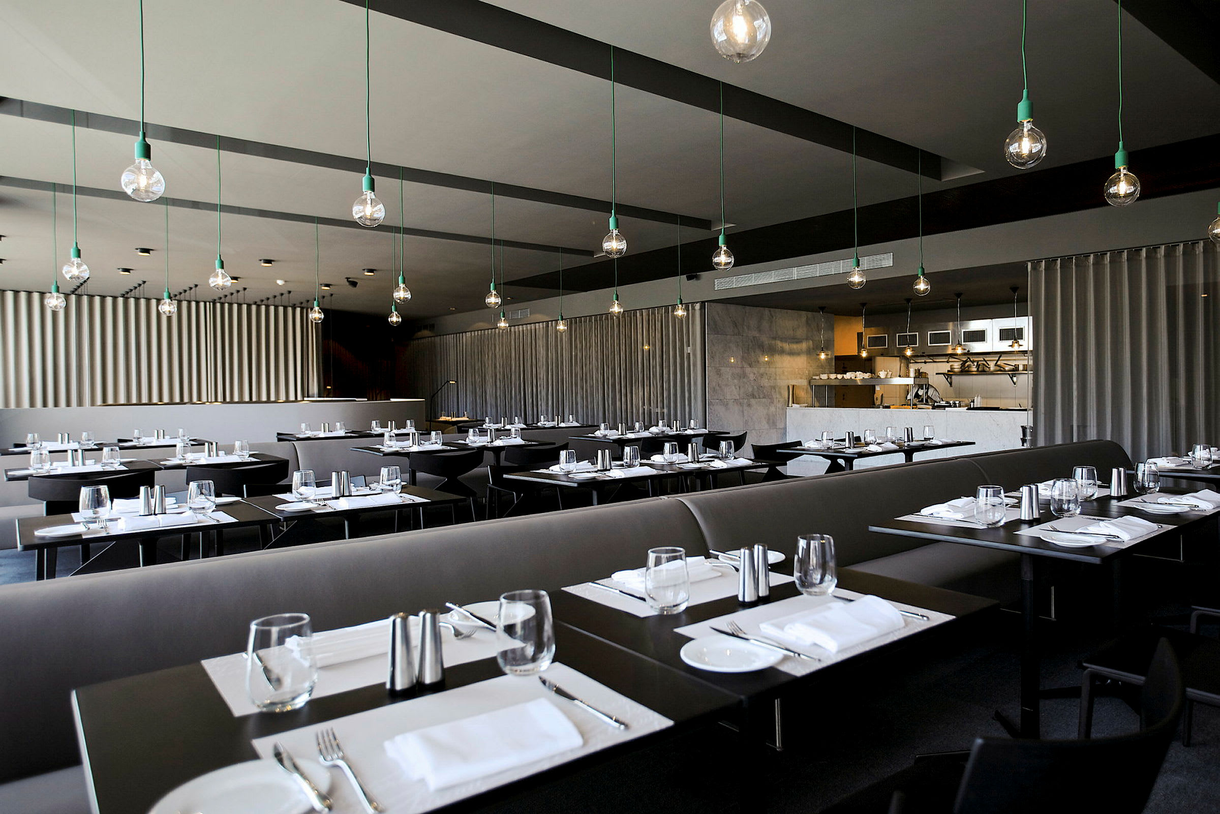 En modern restaurang med mörka bord, dukade för måltid och stilfull takbelysning. (AI-genererad text)