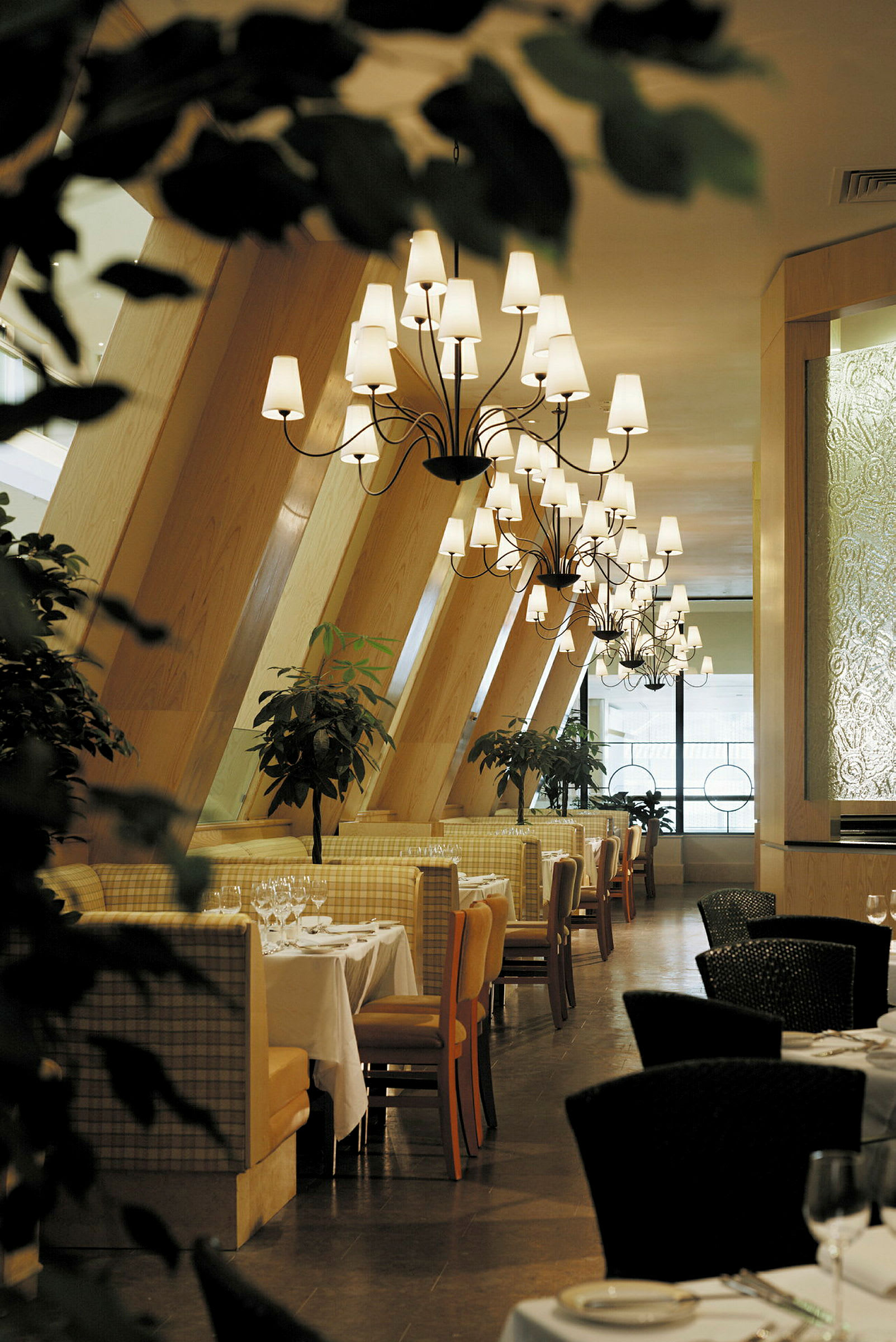Bild av en elegant restaurang med dukade bord, ljuskronor och gröna växter. (AI-genererad text)