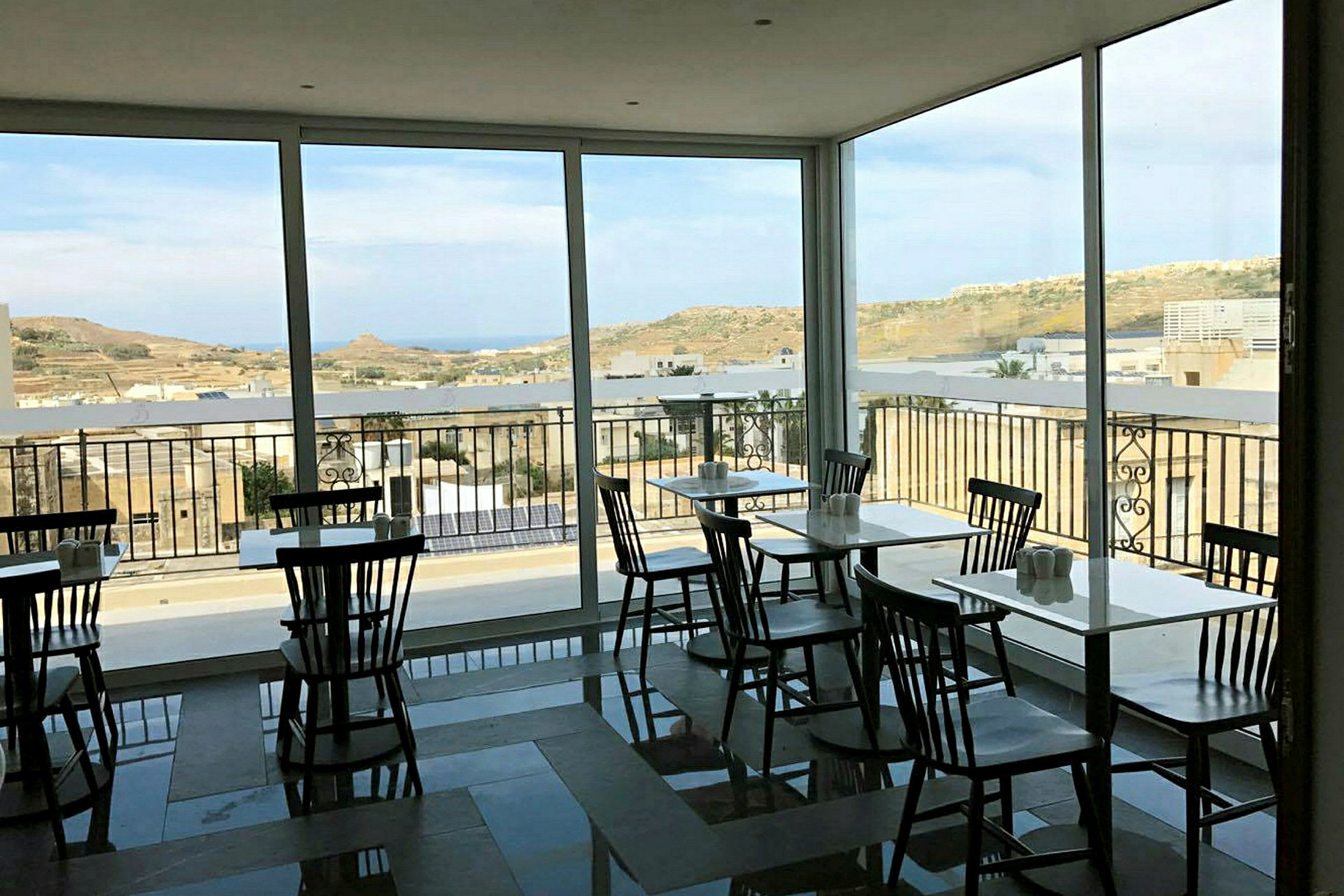 Ett café med stora fönster och utsikt över ett landskap. (AI-genererad text)