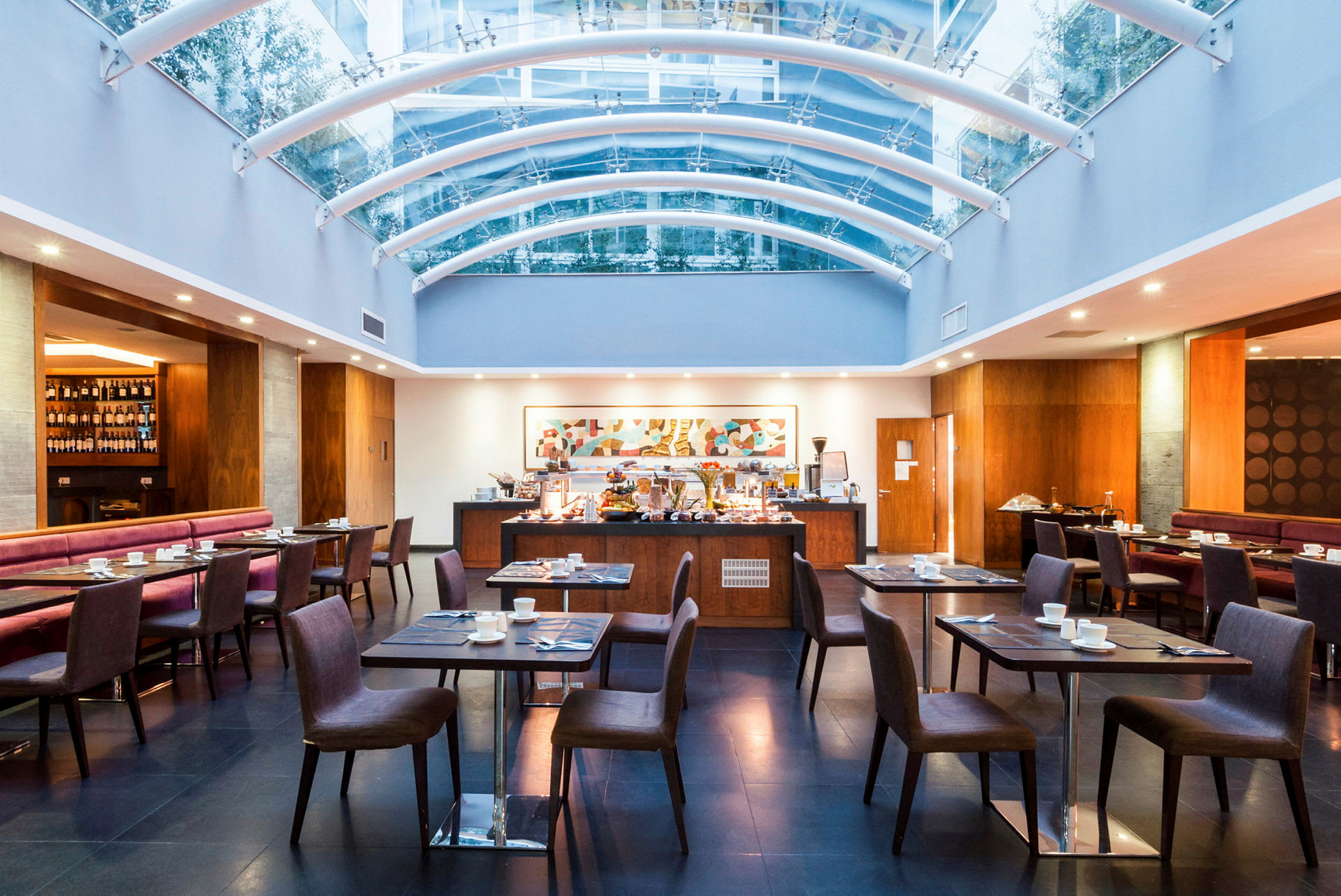 Restaurang med elegant inredning, bord och stolar och genomsiktligt takkonstruktion. (AI-genererad text)