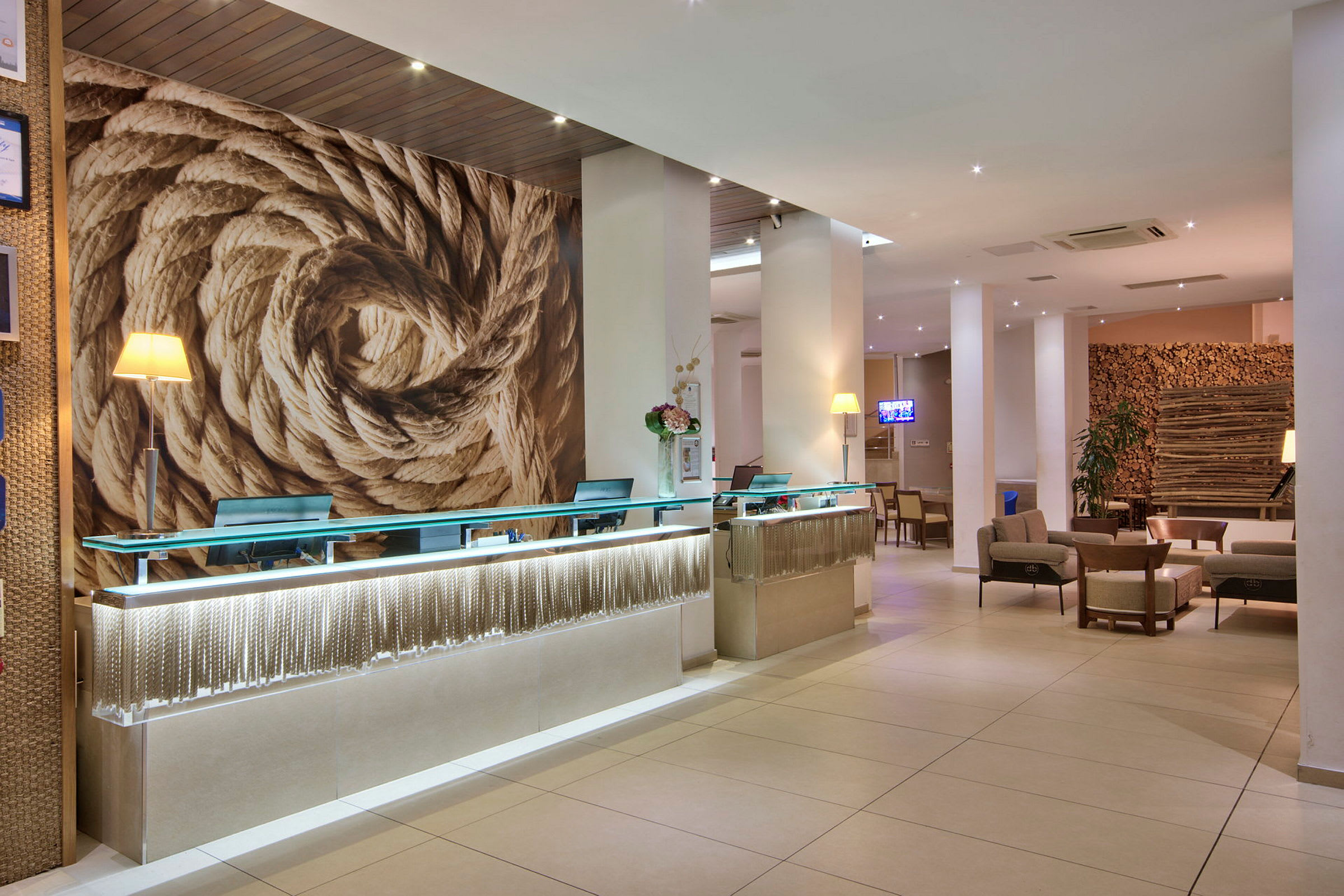 Hotellreception med modern inredning, stora repdekorationer på väggen och sittgrupper i bakgrunden. (AI-genererad text)