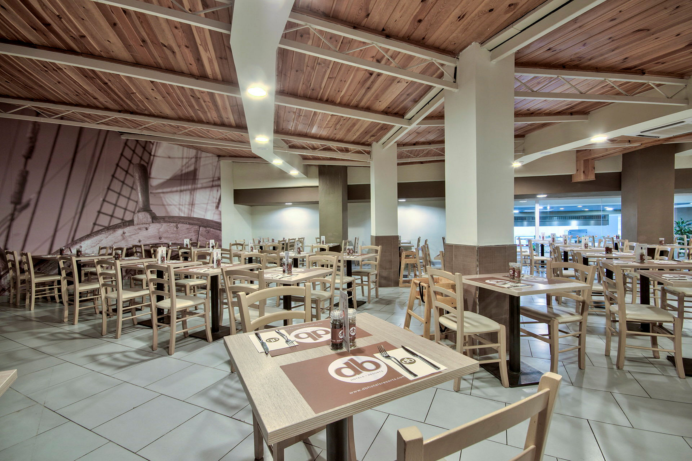 Restaurang med träbord och stolar samt väggdekoration av ett fartyg. (AI-genererad text)