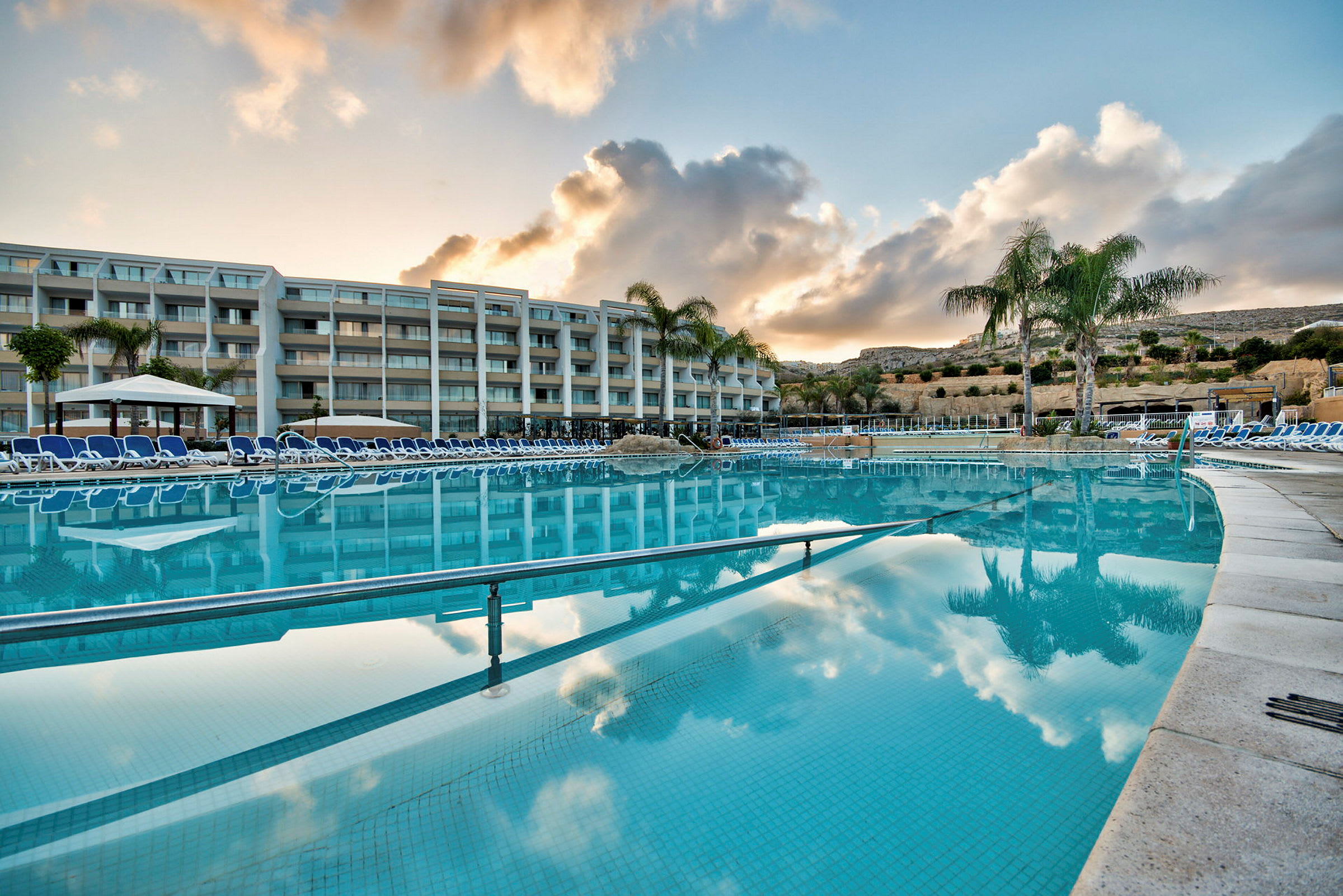 Utomhuspool med solstolar vid ett hotell. (AI-genererad text)