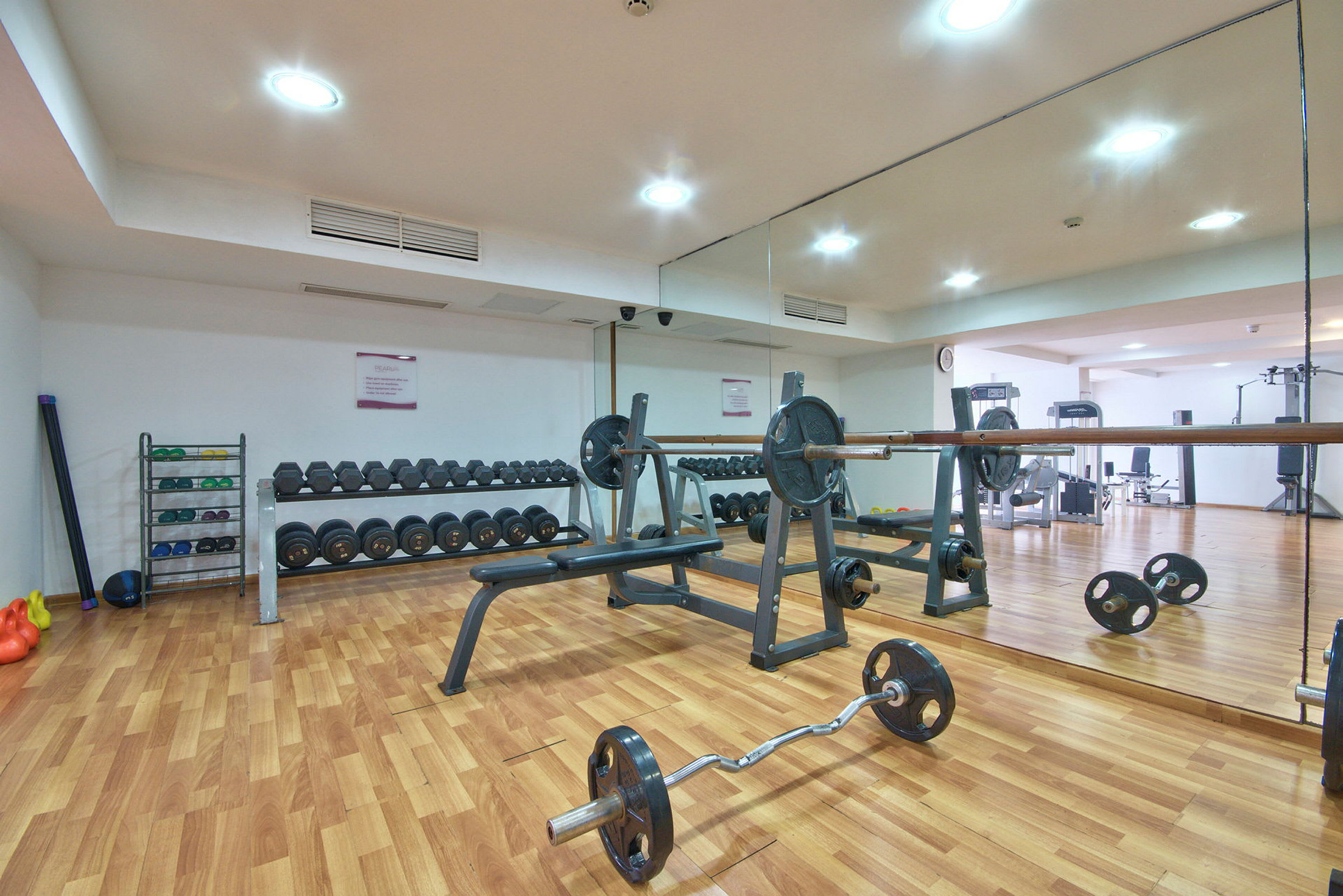 Ett gym med vikter, en bänkpressstation och spegelväggar. (AI-genererad text)