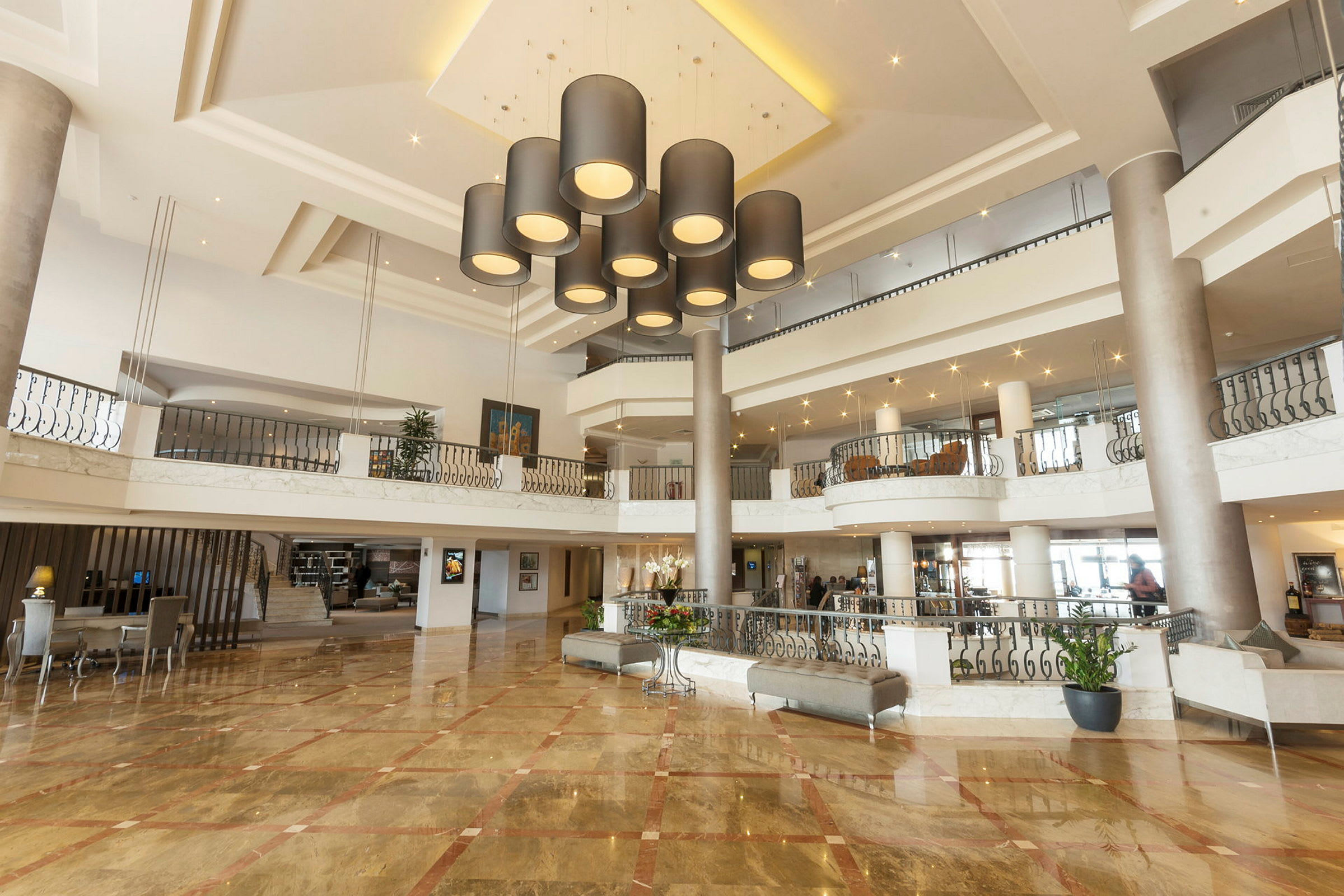 Ett hotellobbymiljö med en elegant taktaklampa, marmorgolv och modern inredning. (AI-genererad text)