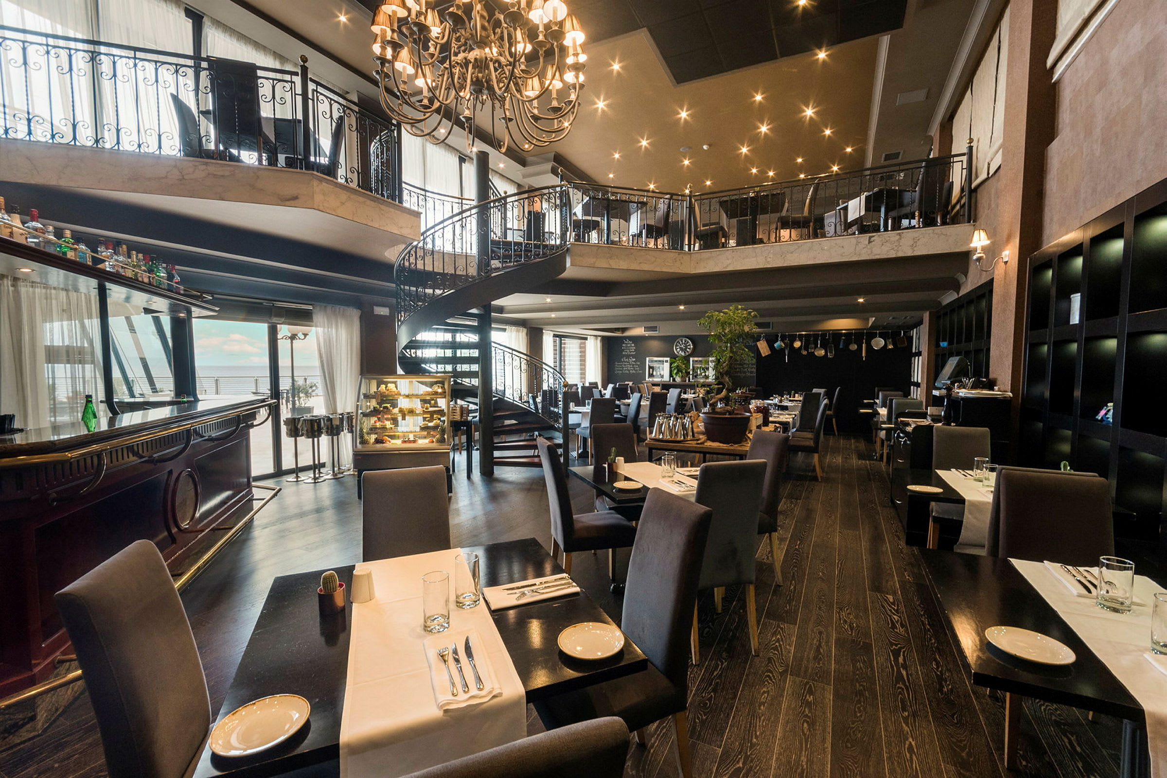 En rymlig restaurang med eleganta möbler och en spiraltrappa i mitten. (AI-genererad text)