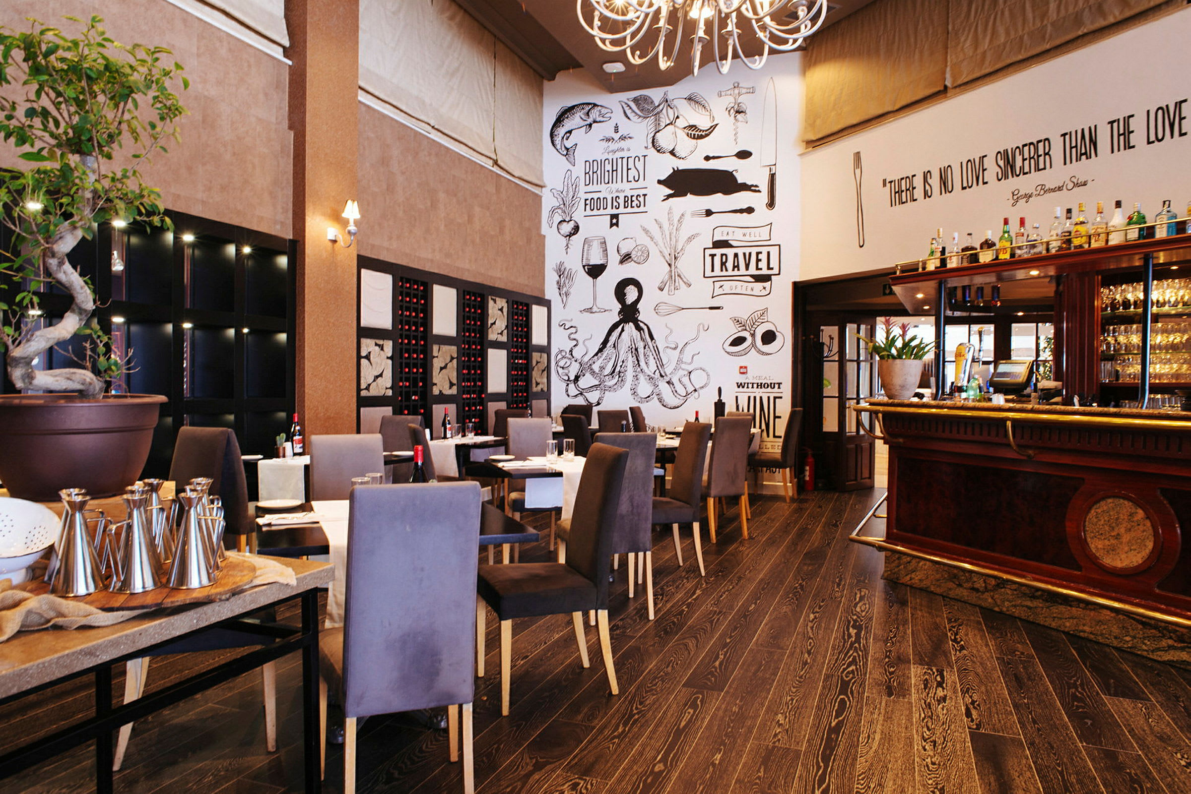 En trevlig restaurang med sittplatser, en dekorativ vägg med texter och teckningar, samt en bar till höger. (AI-genererad text)