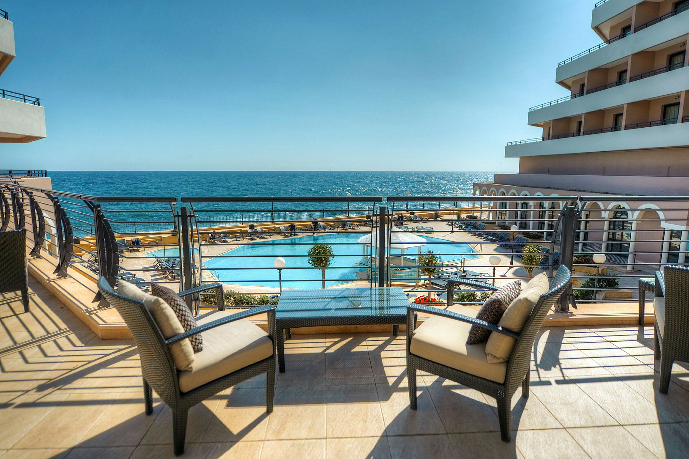 Terrass med utsikt över en pool och havet i bakgrunden. (AI-genererad text)