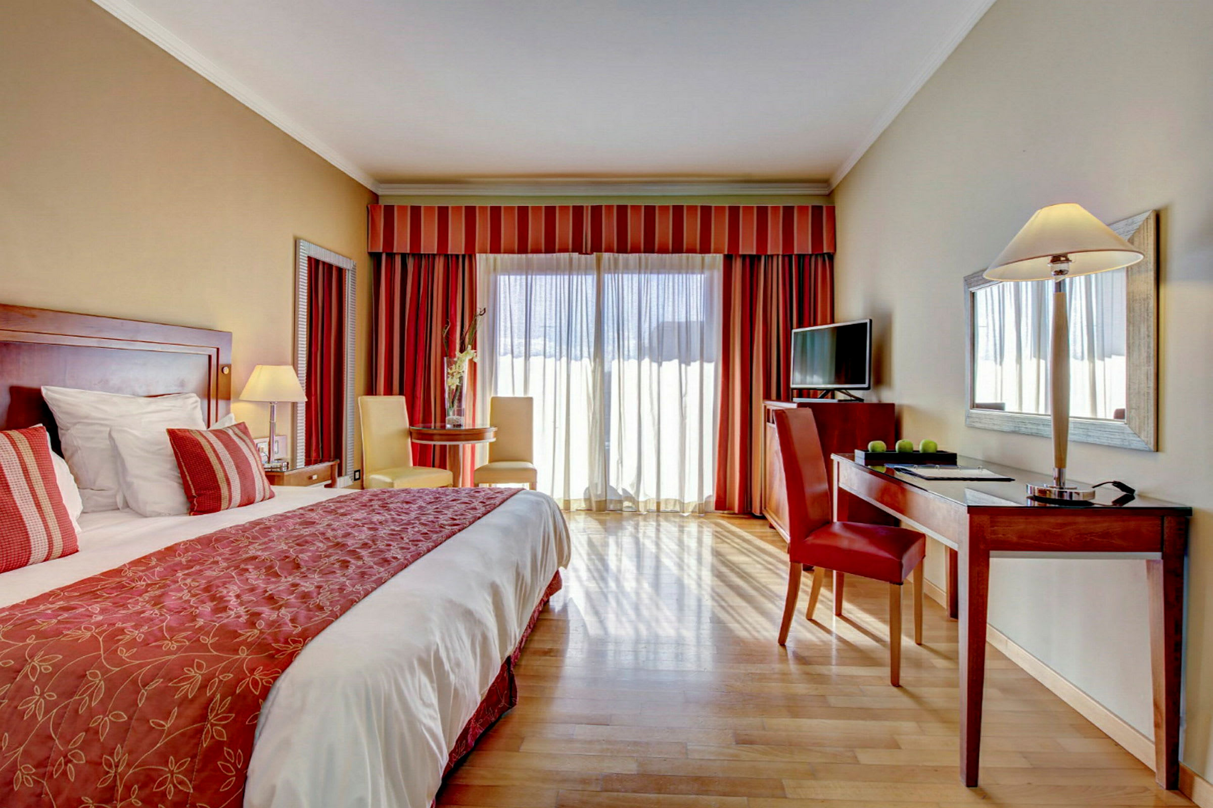 Ett rymligt hotellrum med en dubbelsäng, en skrivbordshörna och ett sittområde bredvid ett stort fönster. (AI-genererad text)