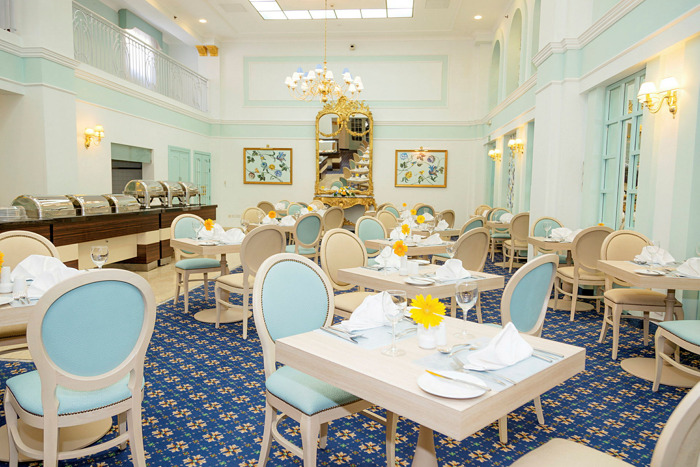 En elegant restaurang med ljusa pastellfärgade möbler, dekorerade bord och en stor guldspegel som pryder väggen. (AI-genererad text)
