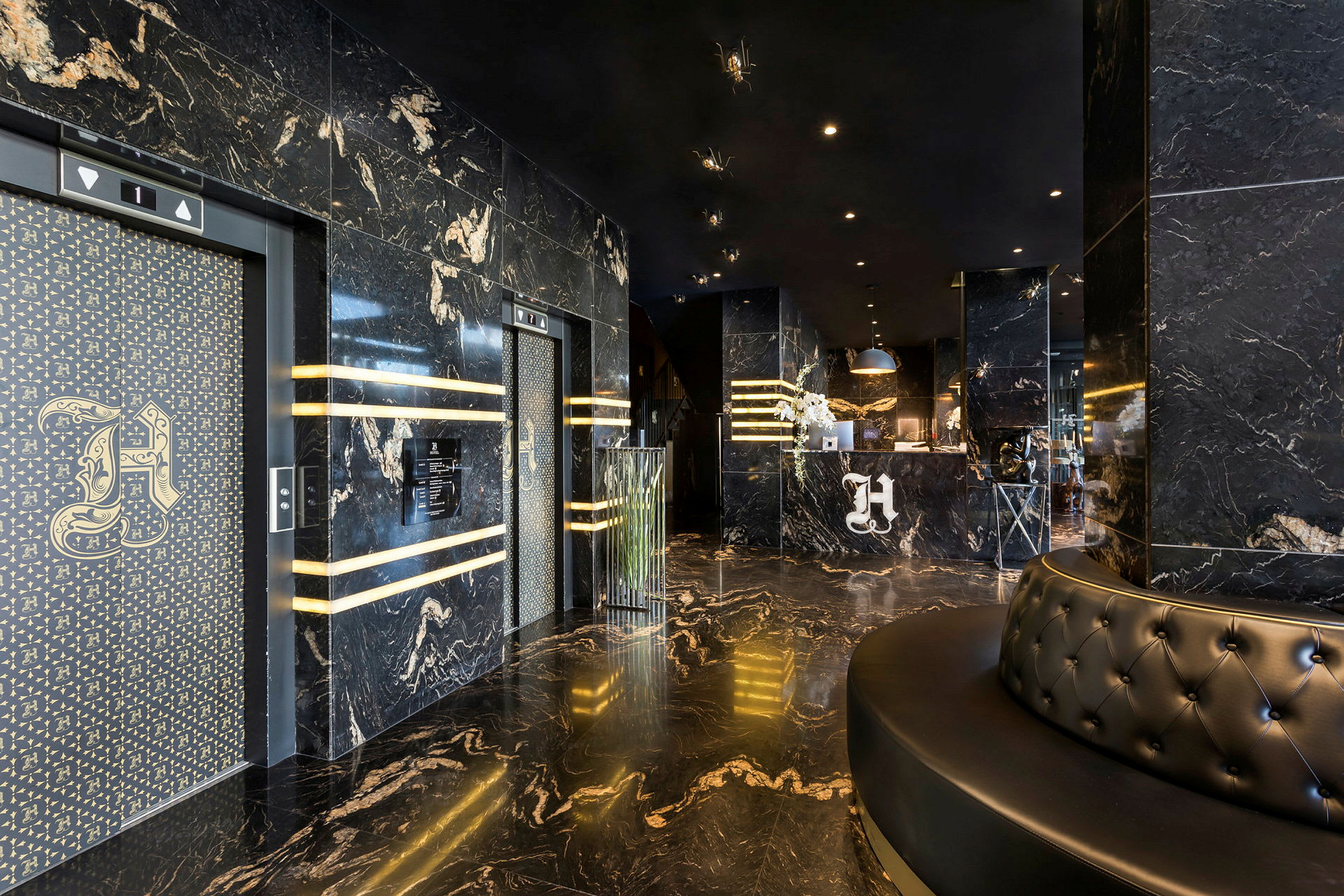 Hotellobby med marmorgolv och marmorklädda väggar. Två hissar till vänster och en reception i bakgrunden. (AI-genererad text)
