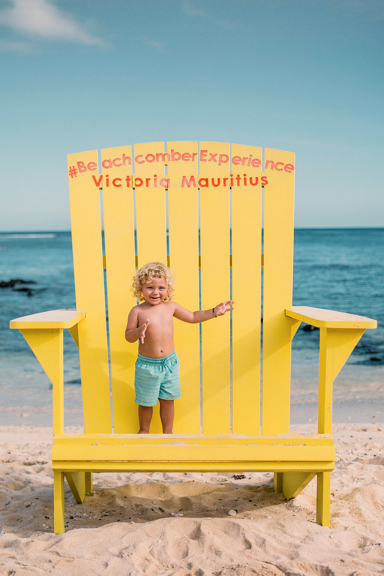 Stor gul stol placerad på en sandstrand framför havet. (AI-genererad text)