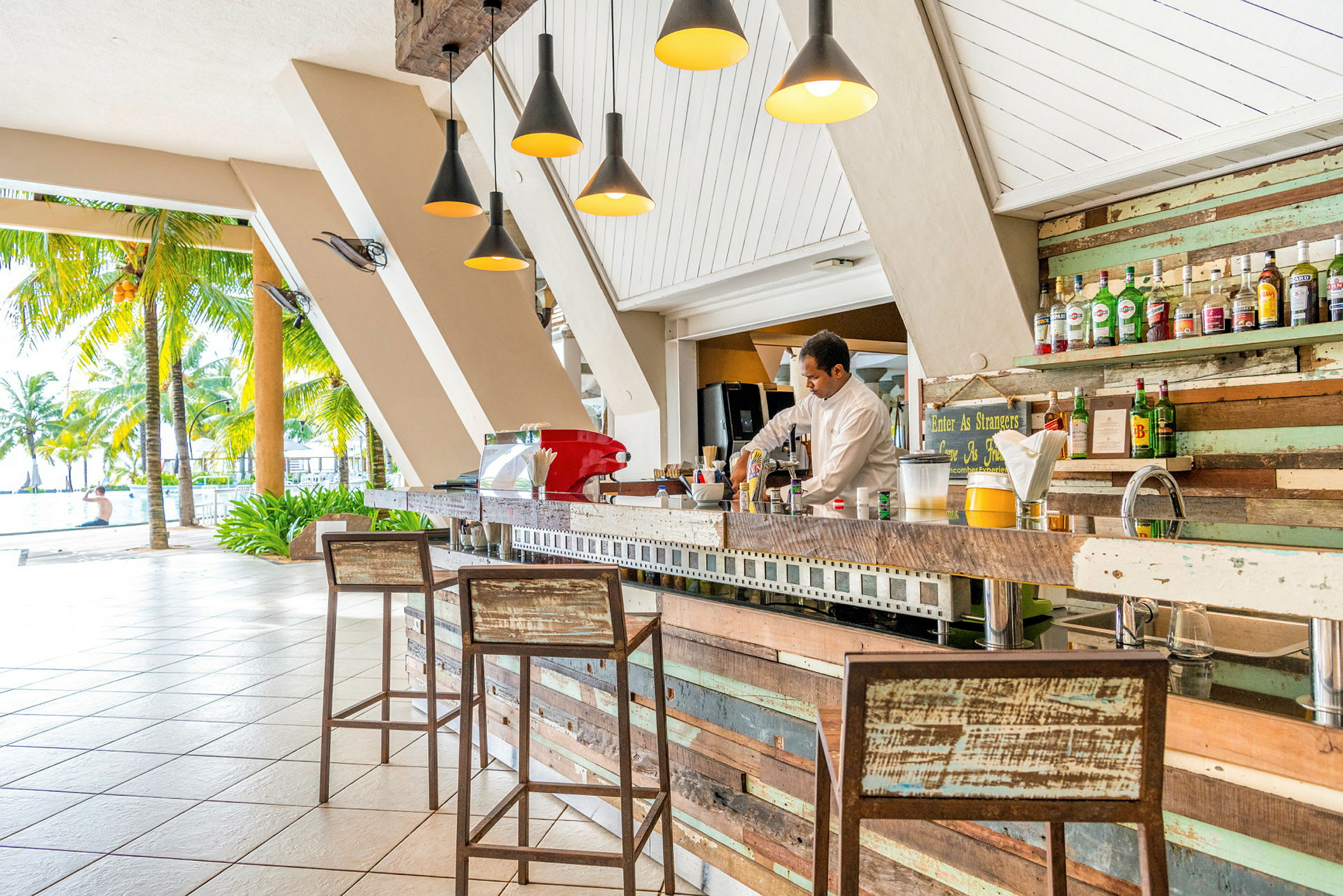En strandnära bar med rustik inredning och flaskor på hyllor. (AI-genererad text)