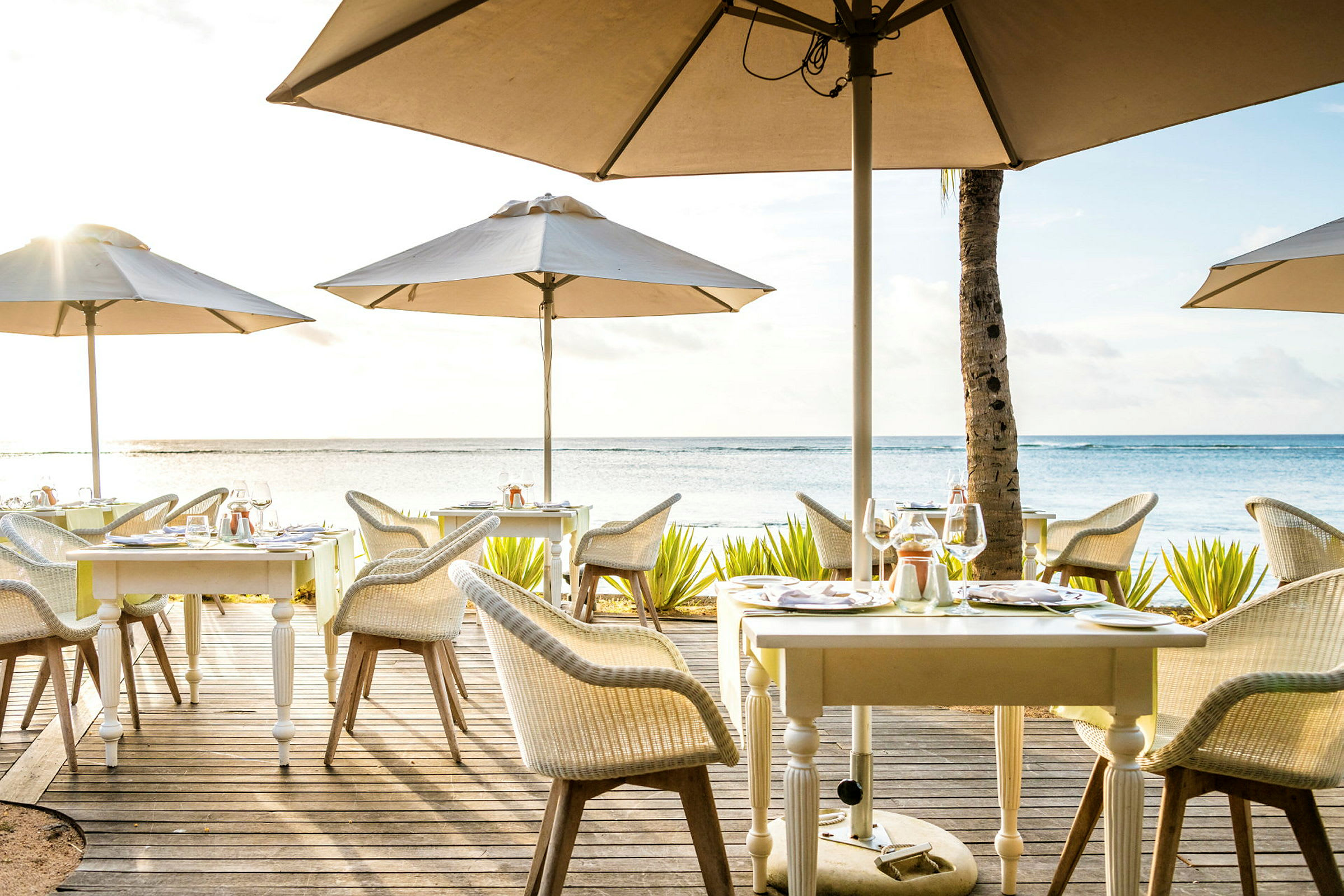 En utomhusrestaurang med bord och parasoller vid havet. (AI-genererad text)