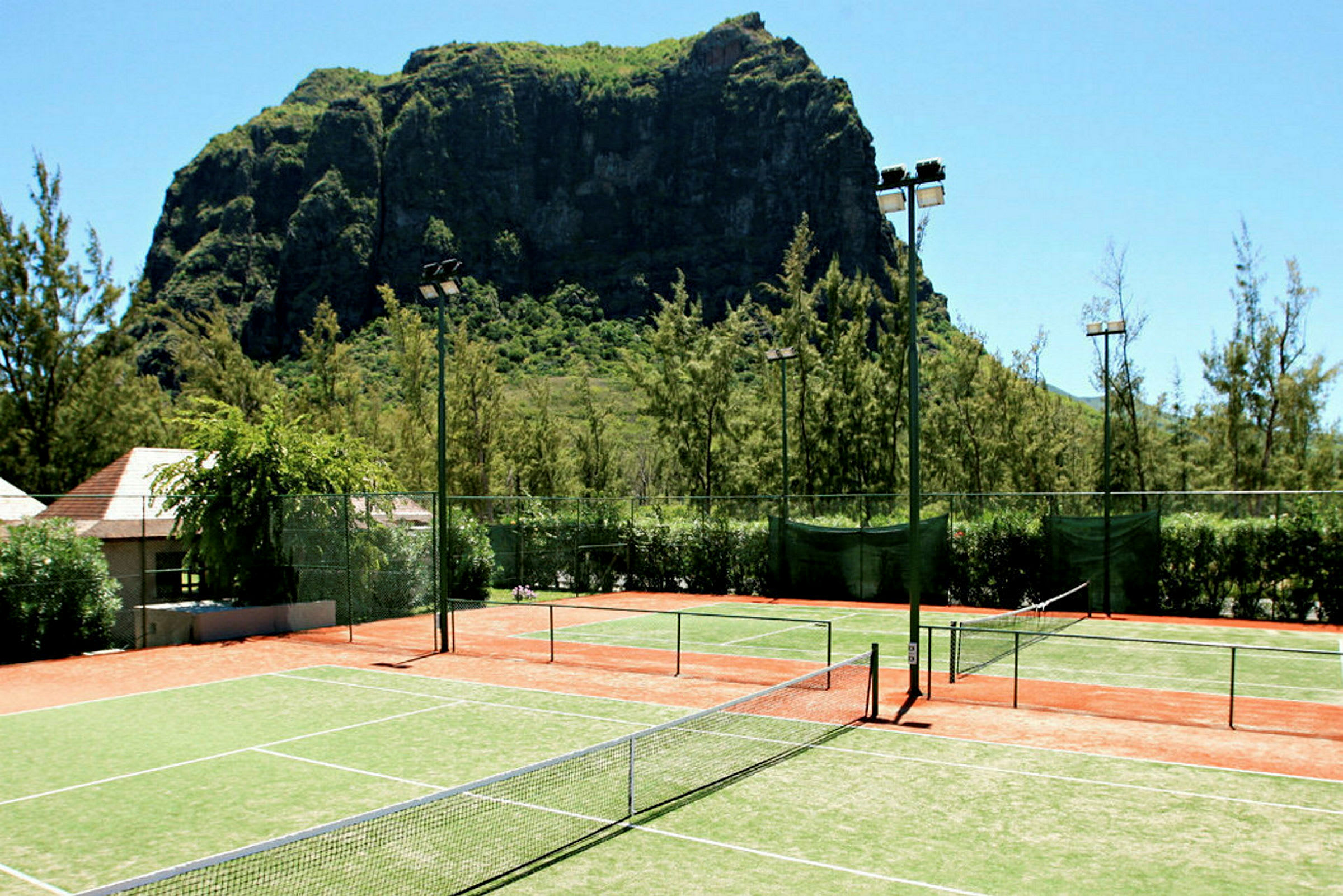 Tennisbanor framför en stor klippa. (AI-genererad text)