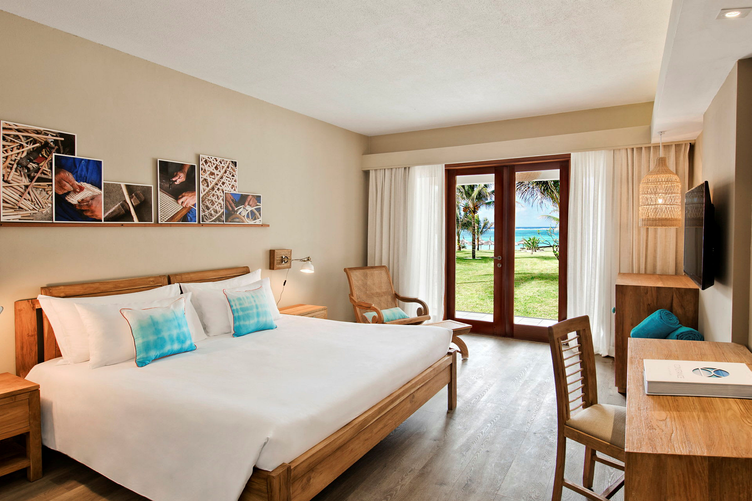 Ett hotellrum med en dubbelsäng, träinredning, och en glasdörr som öppnar upp till en grön trädgård och havsutsikt. (AI-genererad text)