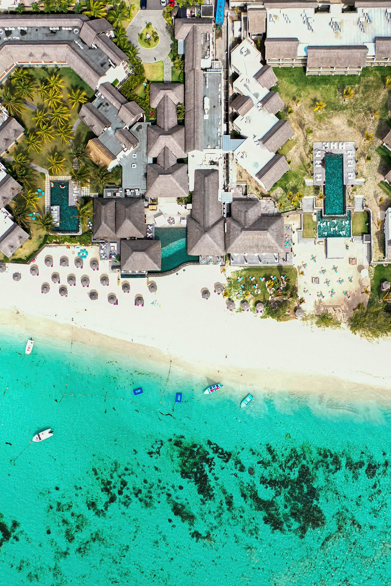 Flygfoto av ett hotellkomplex vid en strand med turkost vatten. (AI-genererad text)