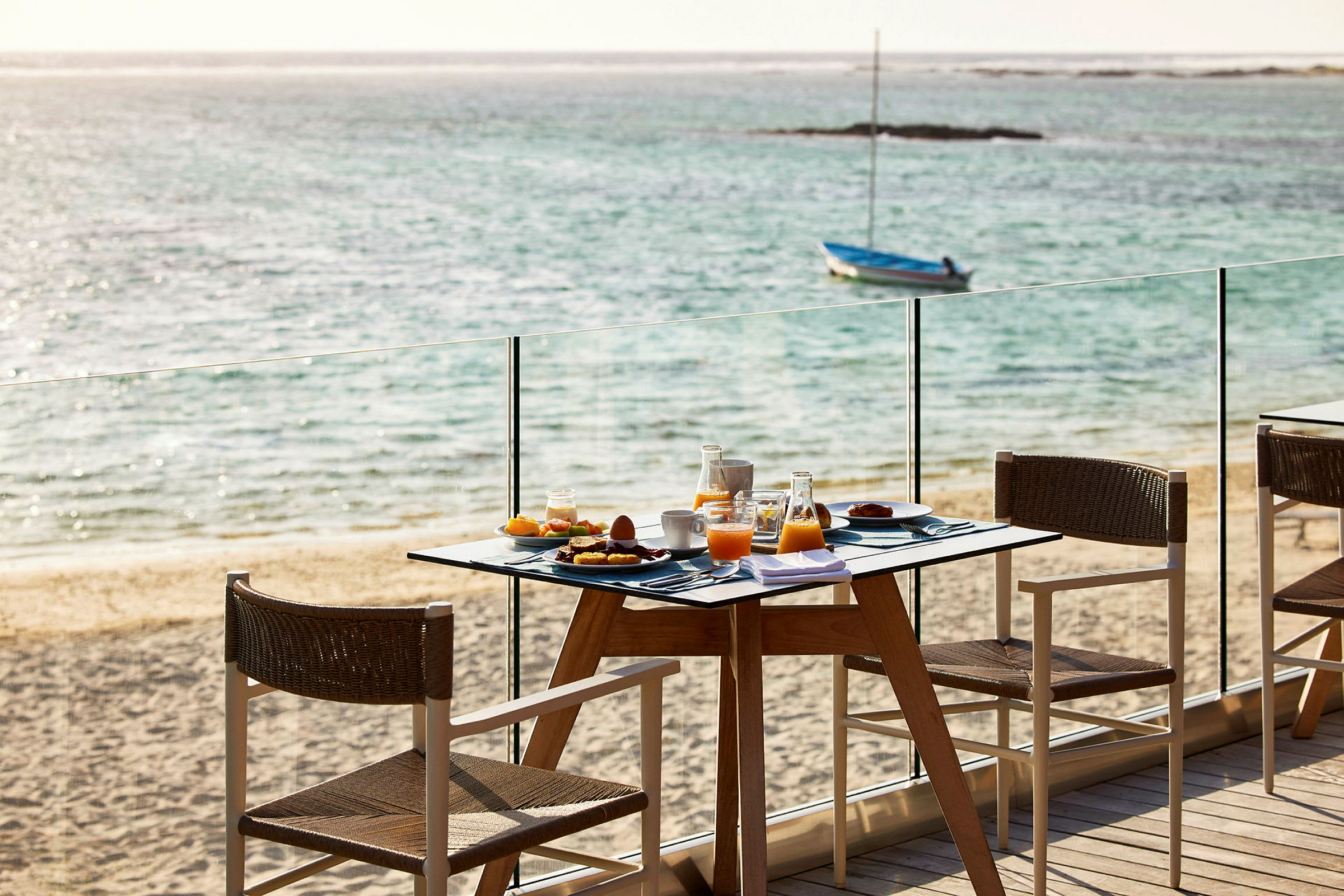 En frukost serveras vid ett bord nära stranden med havet i bakgrunden. (AI-genererad text)