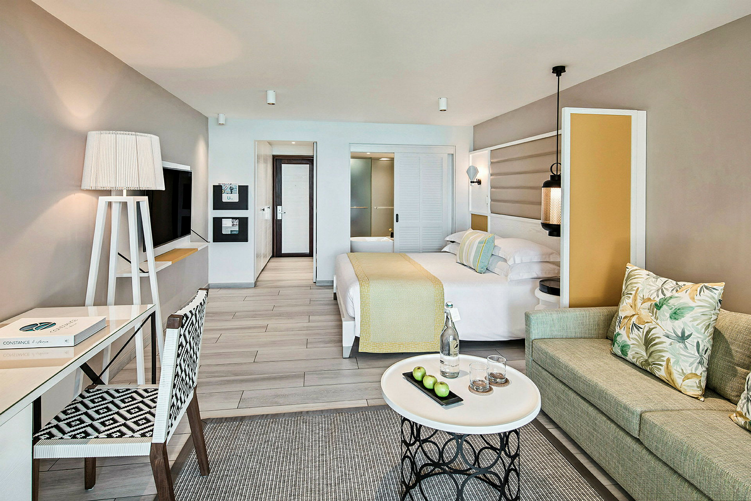 Ett hotellrum med modern inredning, säng, skrivbord, soffa och ett soffbord. (AI-genererad text)