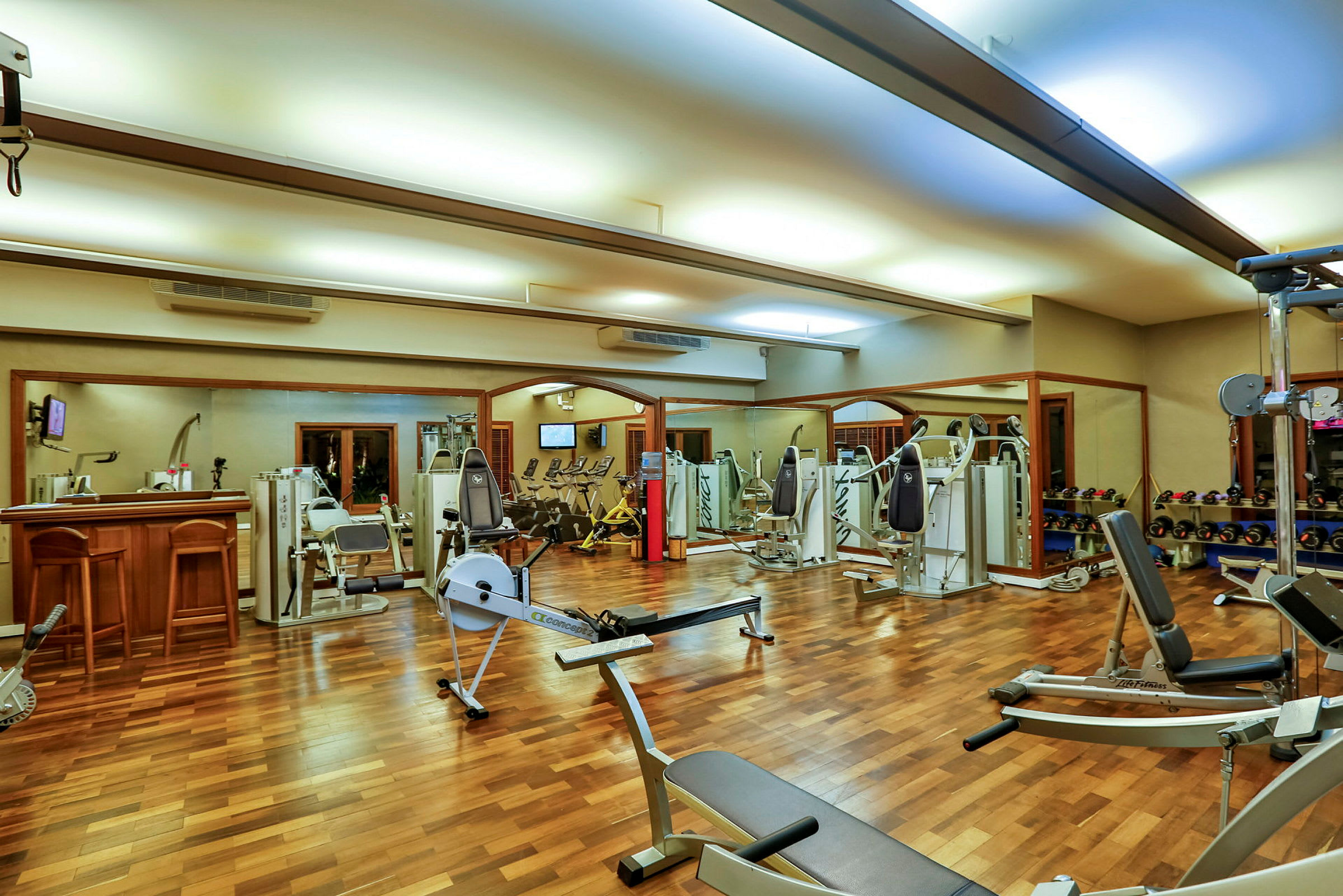 Ett gym med träningsmaskiner och fria vikter på ett trägolv. (AI-genererad text)
