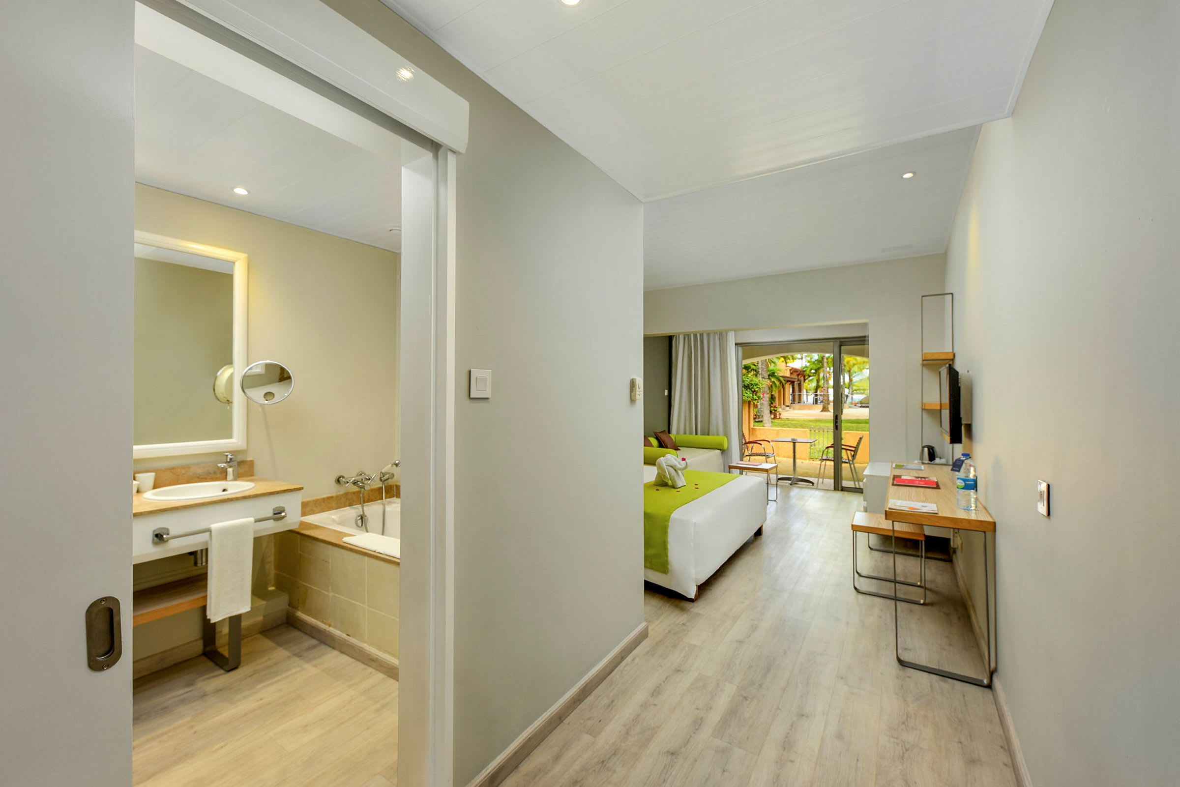 Ett hotellrum med ett badrum, säng och sittgrupp med utgång till en möblerad terrass. (AI-genererad text)