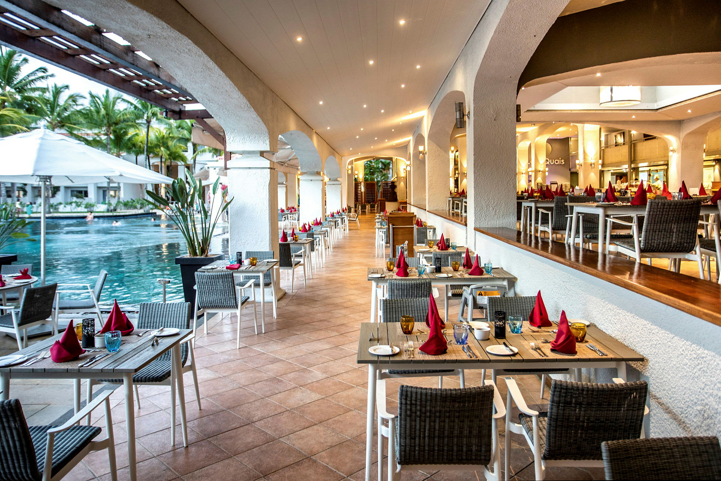 Restaurang med bord och stolar nära en pool. (AI-genererad text)