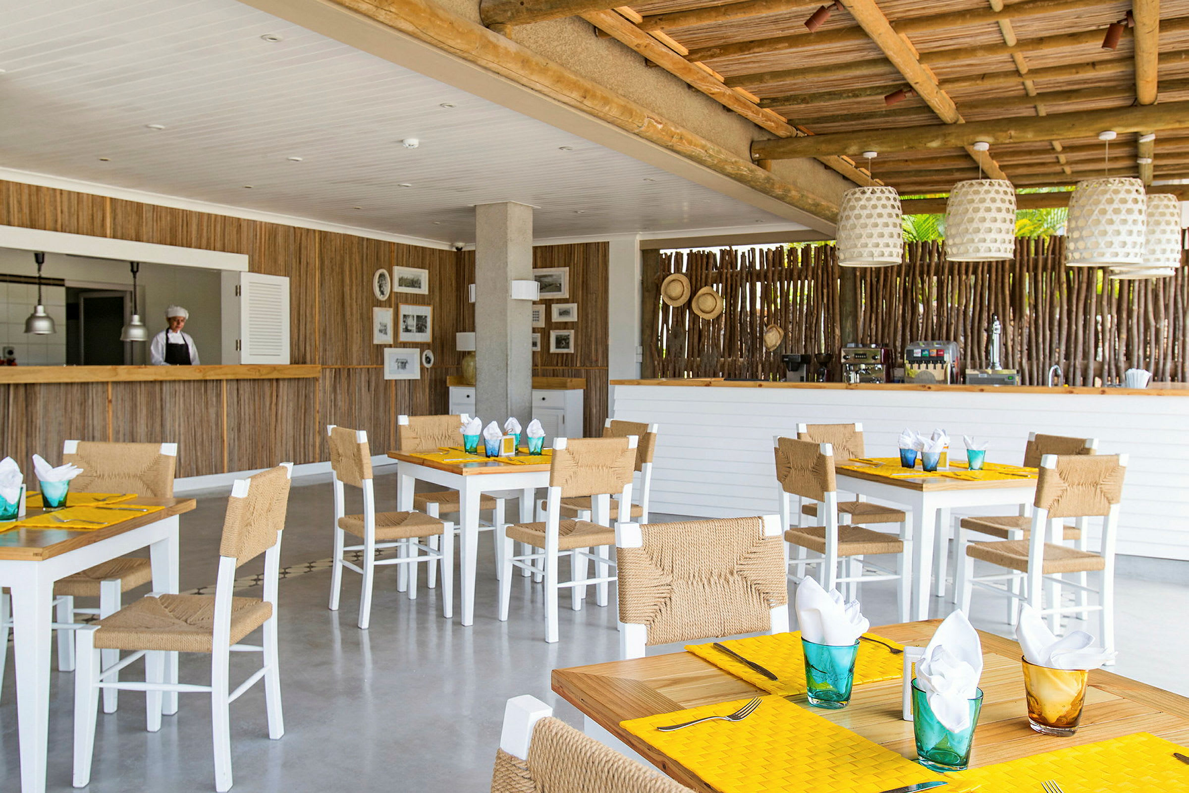 En restaurang med träinredning, vita bord och stolar, och dukade bord. (AI-genererad text)