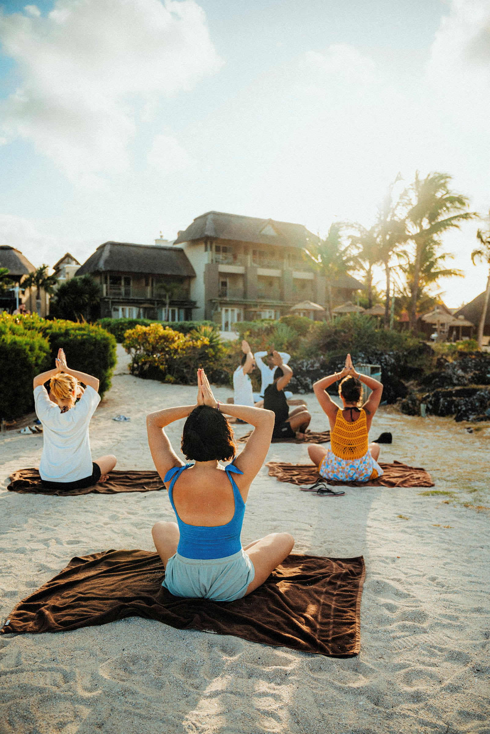 Personer utövar yoga på en sandstrand. (AI-genererad text)