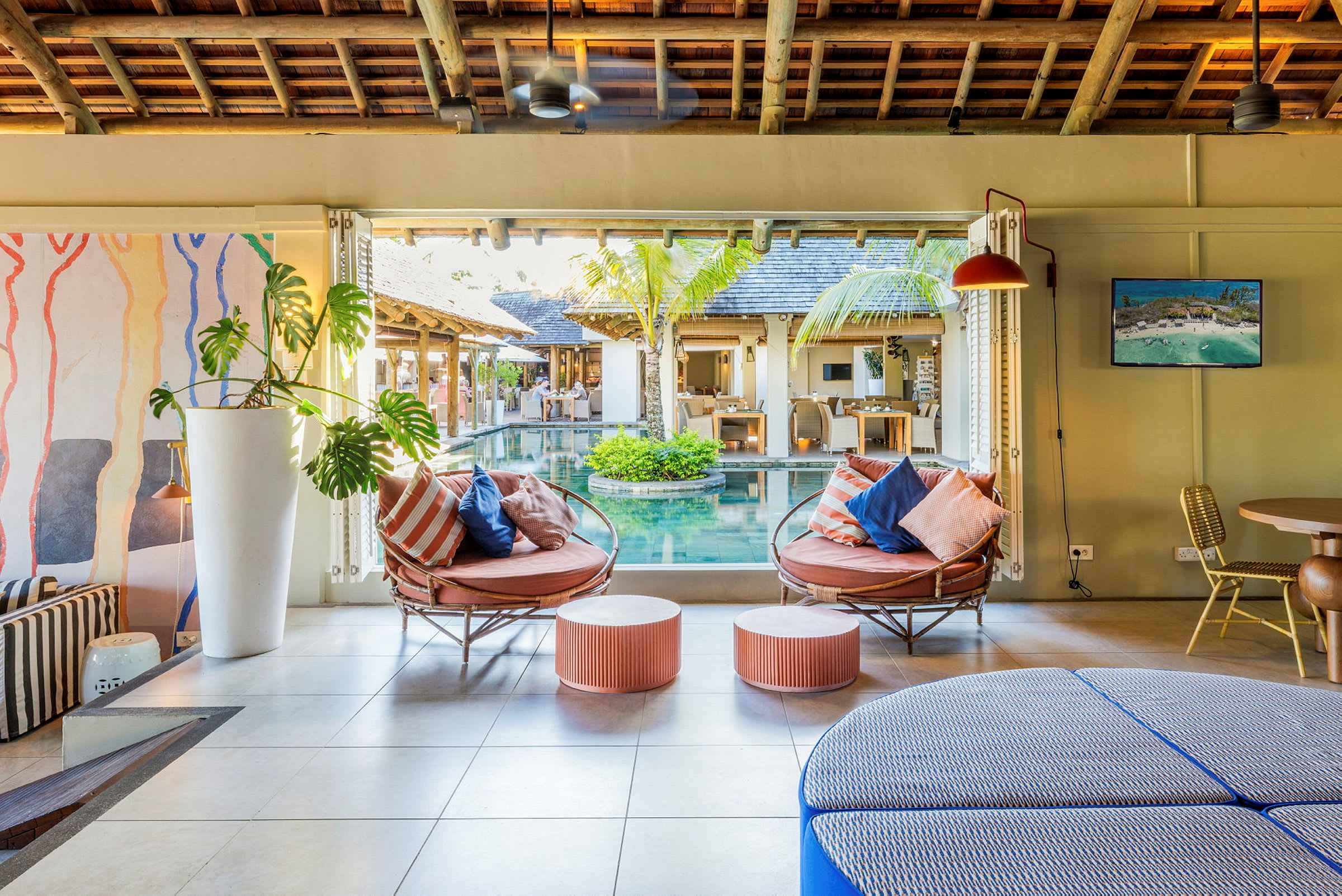 Loungemöbler med kuddar i en inomhusmiljö bredvid en pool. (AI-genererad text)