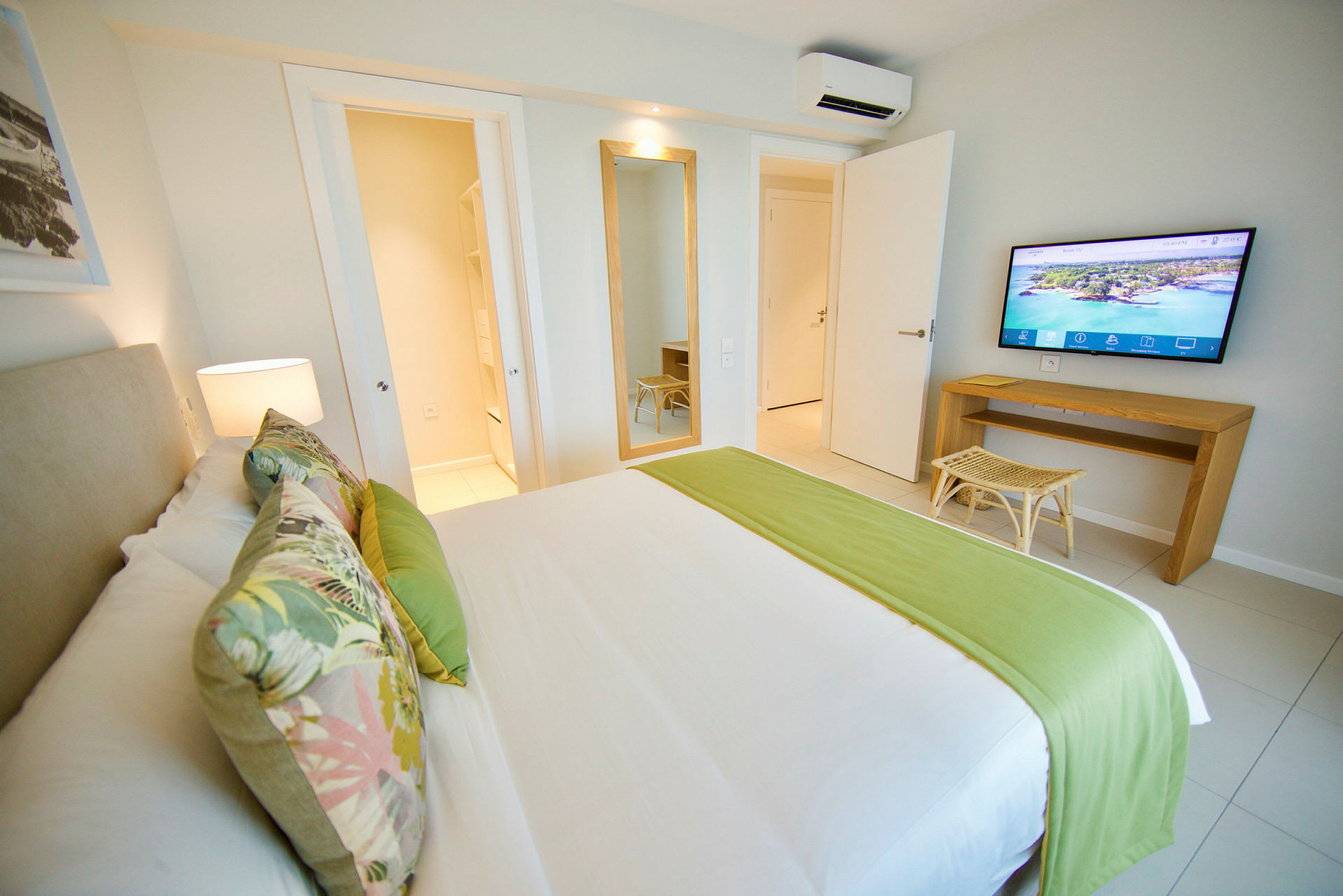 Ett hotellrum med en säng, väggspegel och TV. (AI-genererad text)