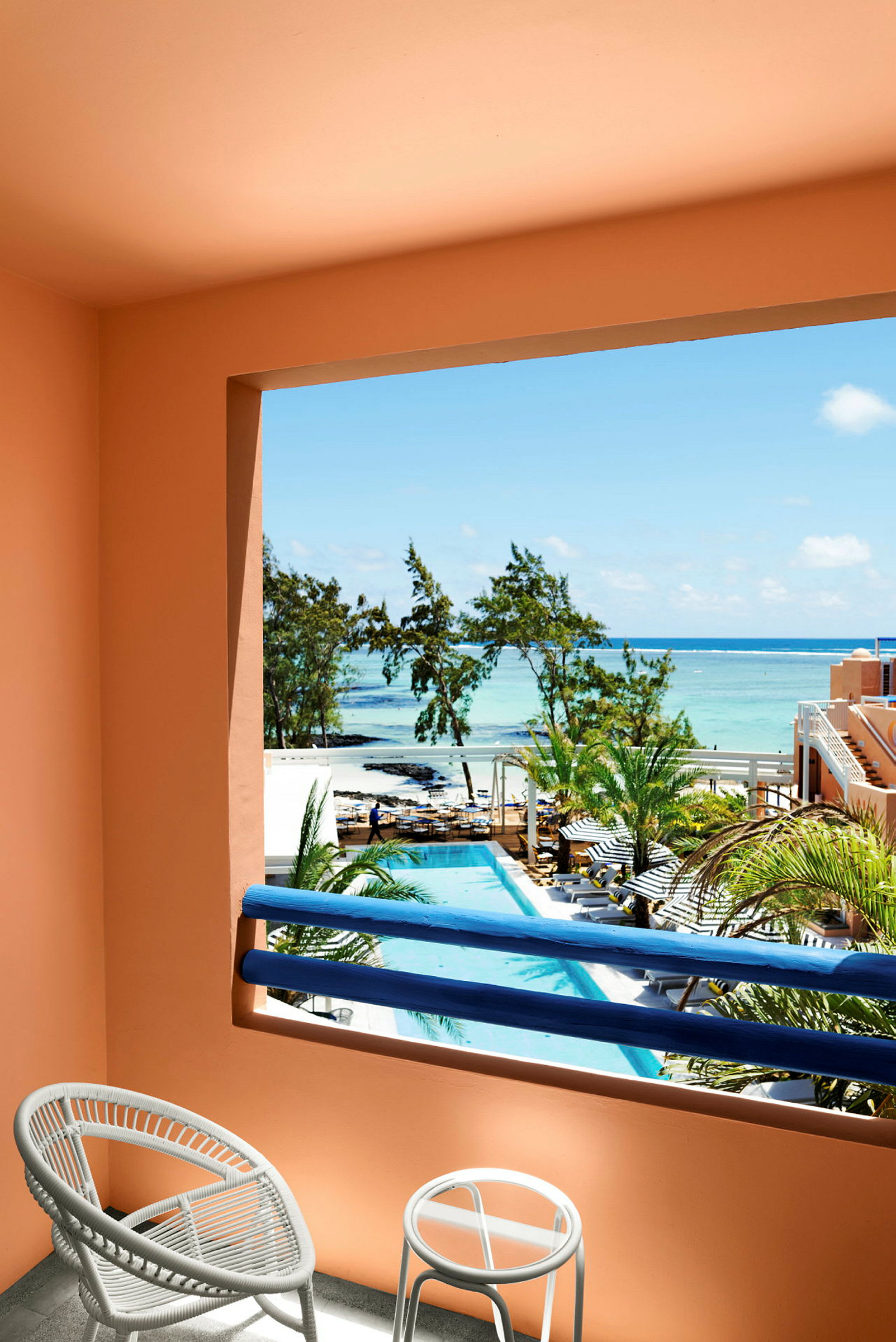 Utsikt från en balkong med stolar, över en pool och mot havet. (AI-genererad text)