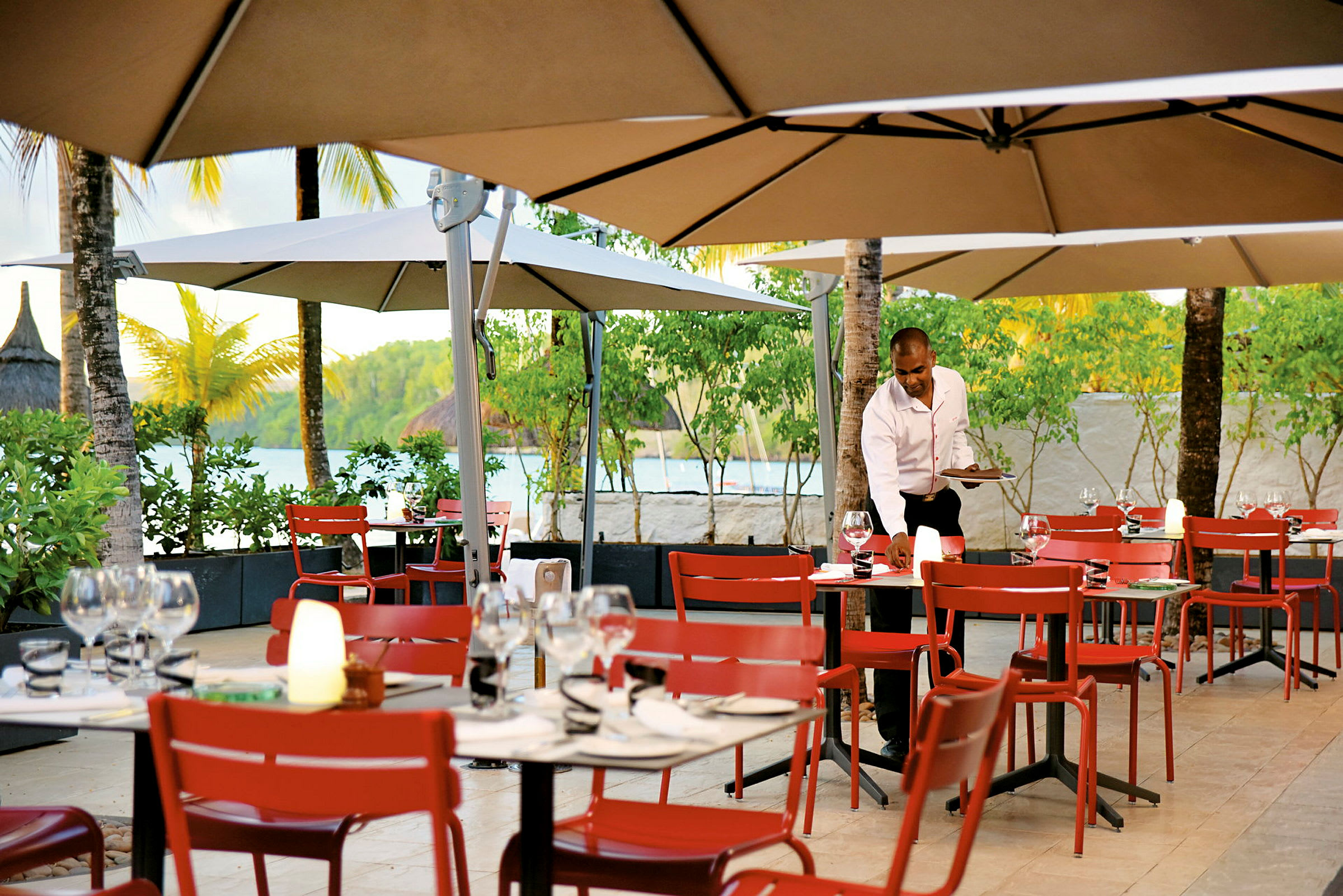 Restaurang med uteservering, röda stolar och bord under parasoller. (AI-genererad text)