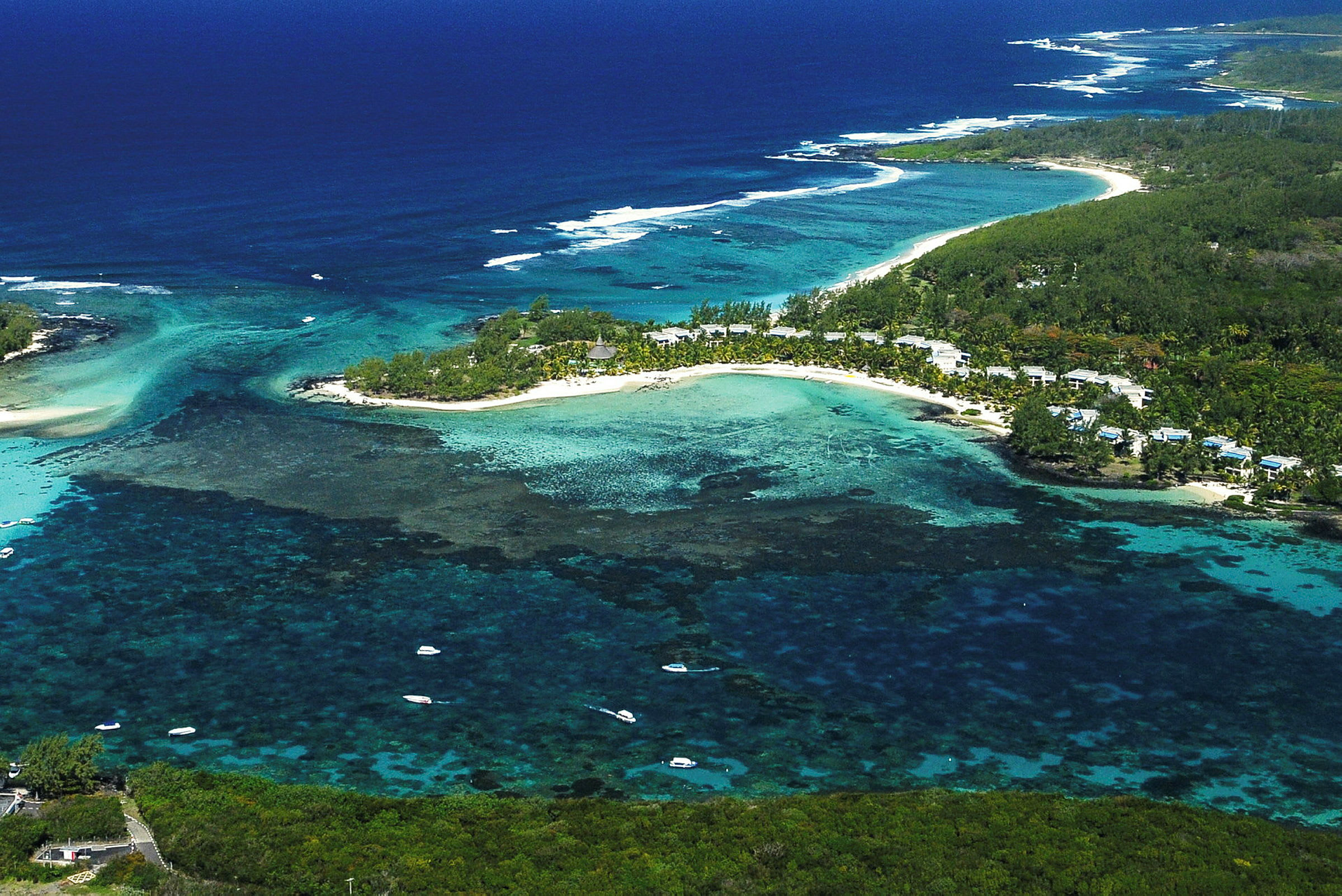 Flygvy över kustlandskap med sandstrand, turkost vatten och grönskande vegetation. (AI-genererad text)