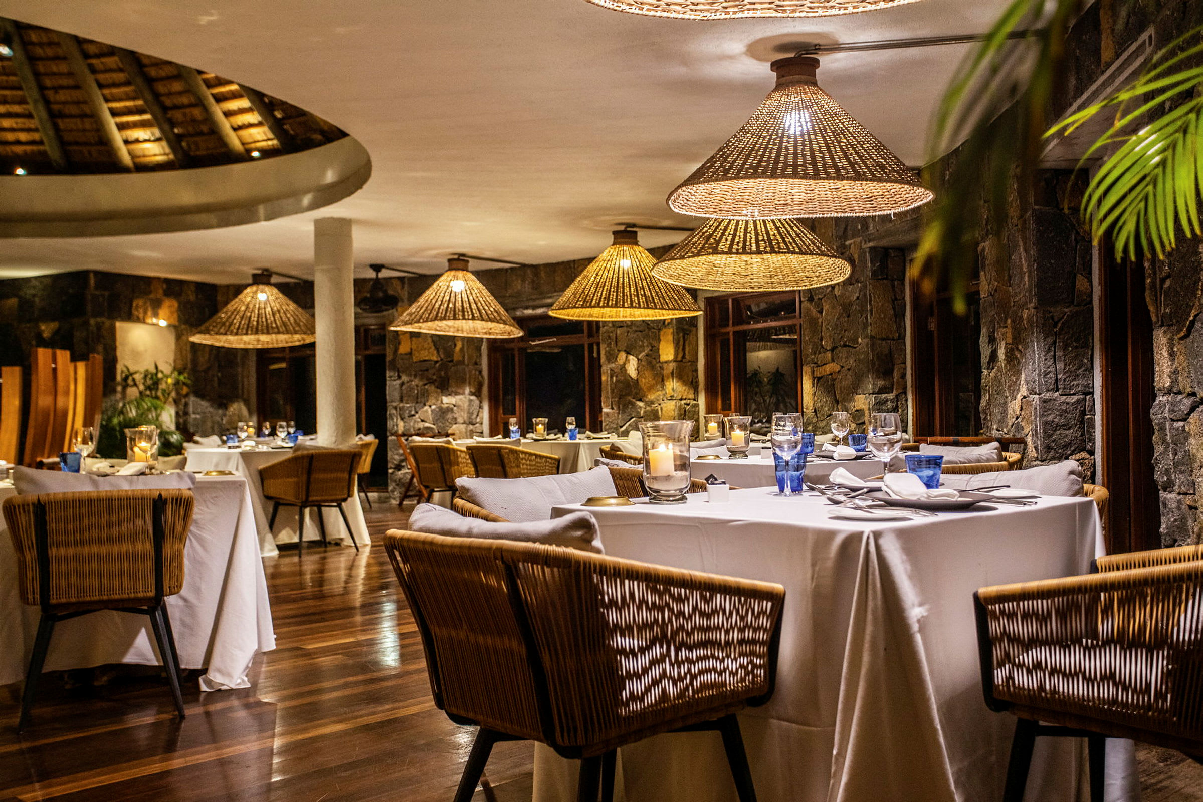 En elegant restaurang med dukade bord och rottinglampor. (AI-genererad text)