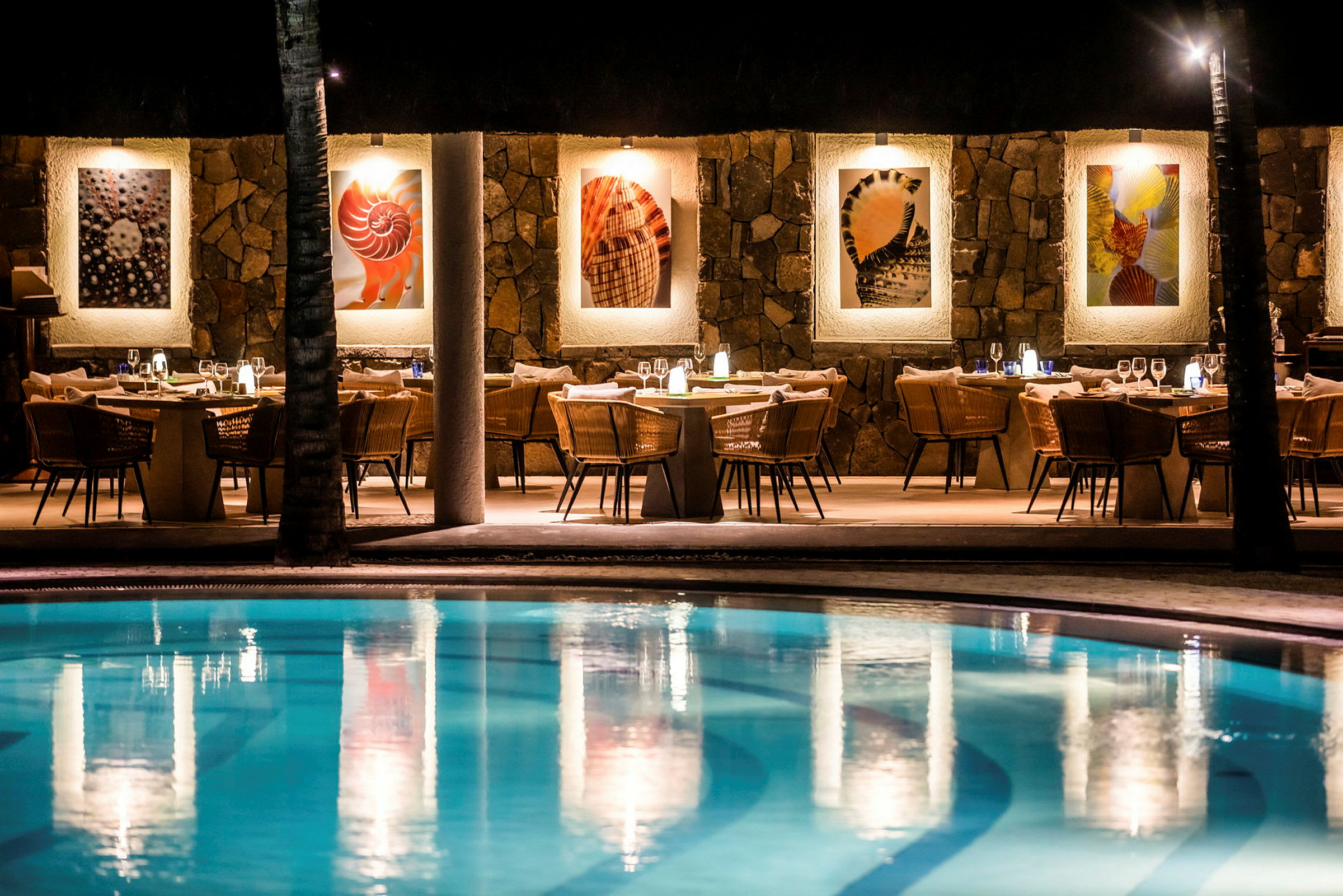 Restaurang med pool i förgrunden, belysning och väggdekorationer synliga. (AI-genererad text)