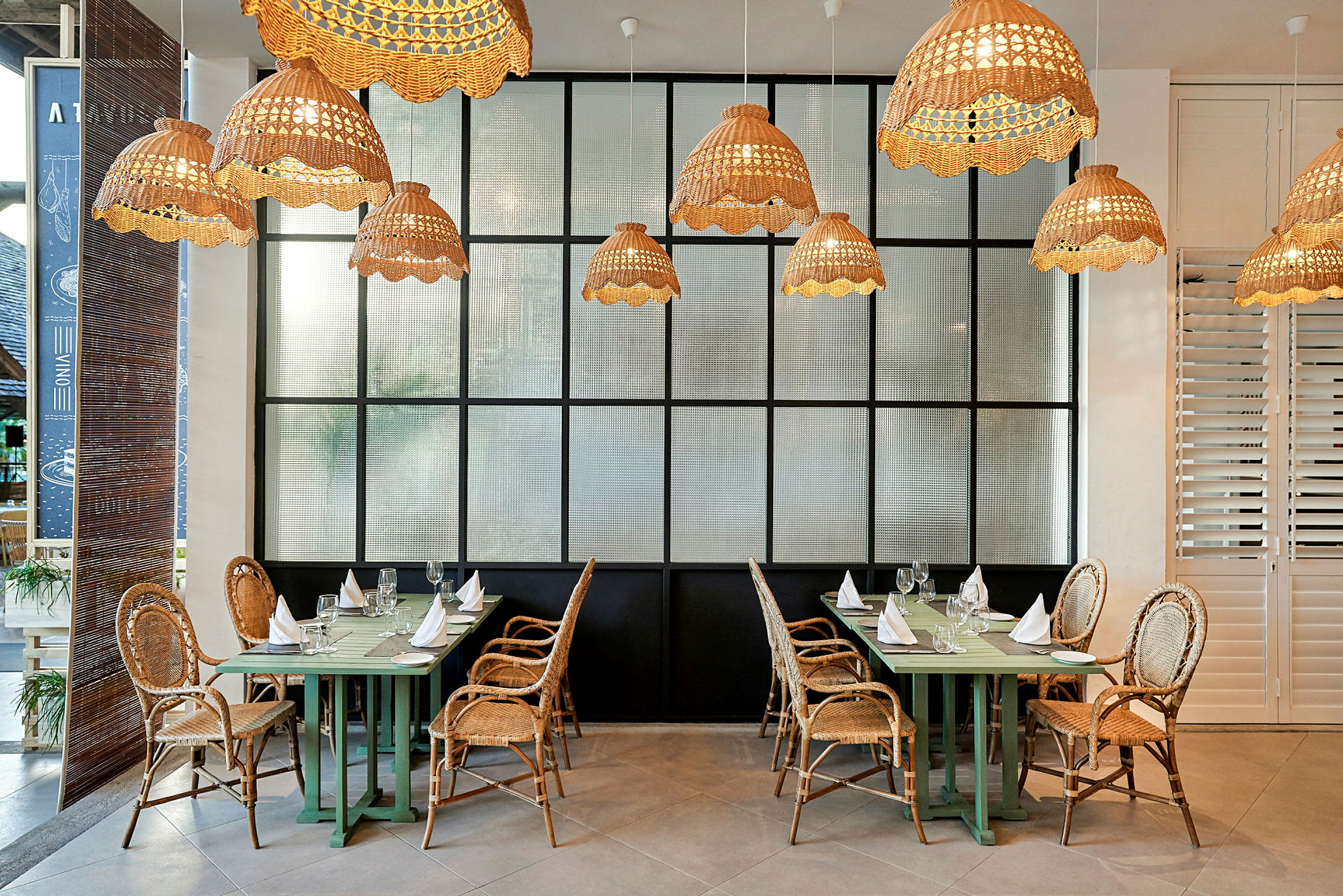 Restaurang med rottingstolar och hängande lampor. (AI-genererad text)
