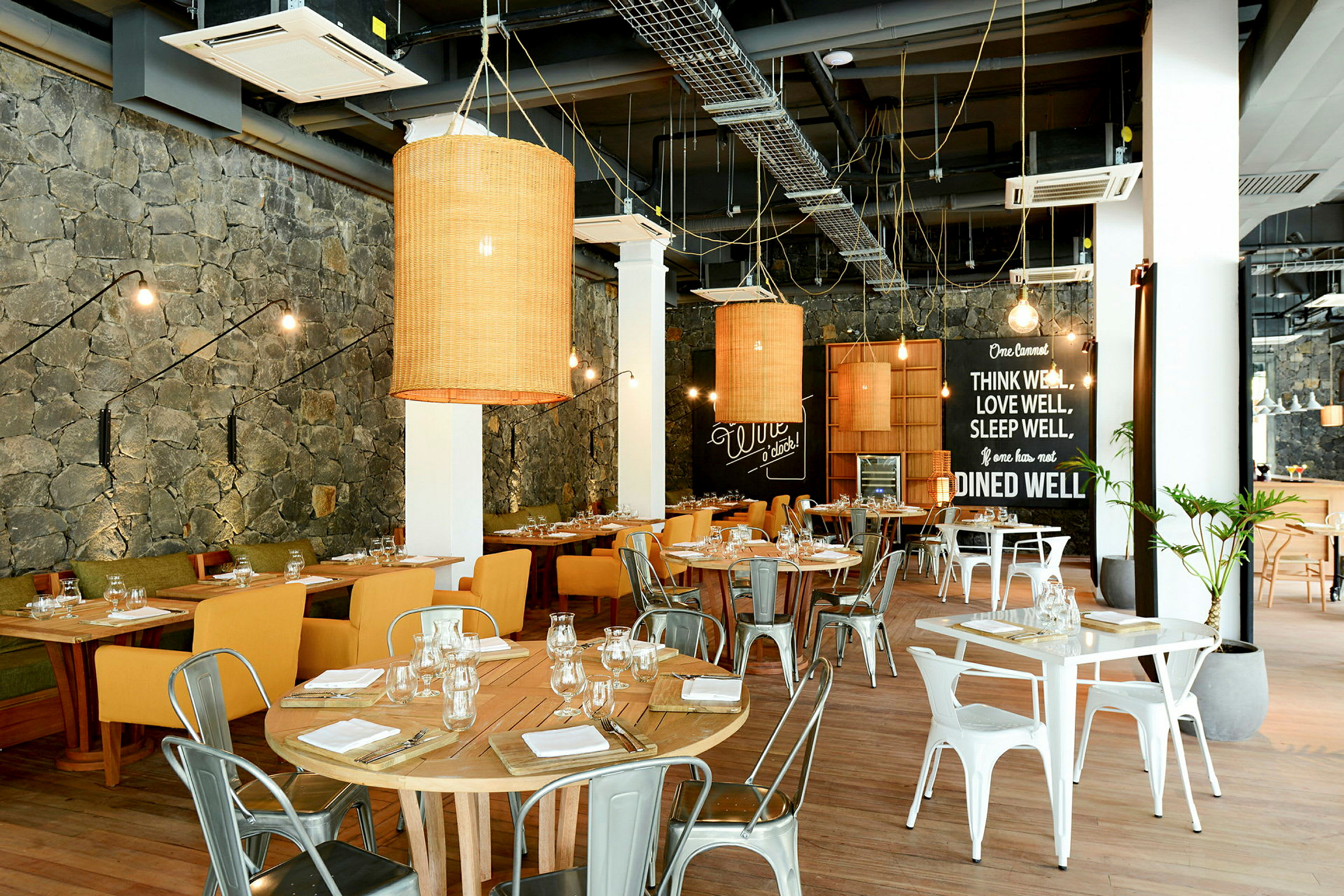 En inomhusrestaurang med träbord och stolar, dekorerad med vägglampor och stora lampor. (AI-genererad text)