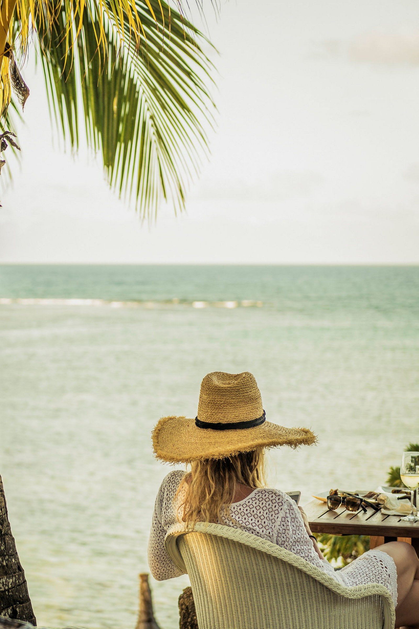 En person sitter i en stol, iklädd en solhatt, med utsikt över havet. (AI-genererad text)