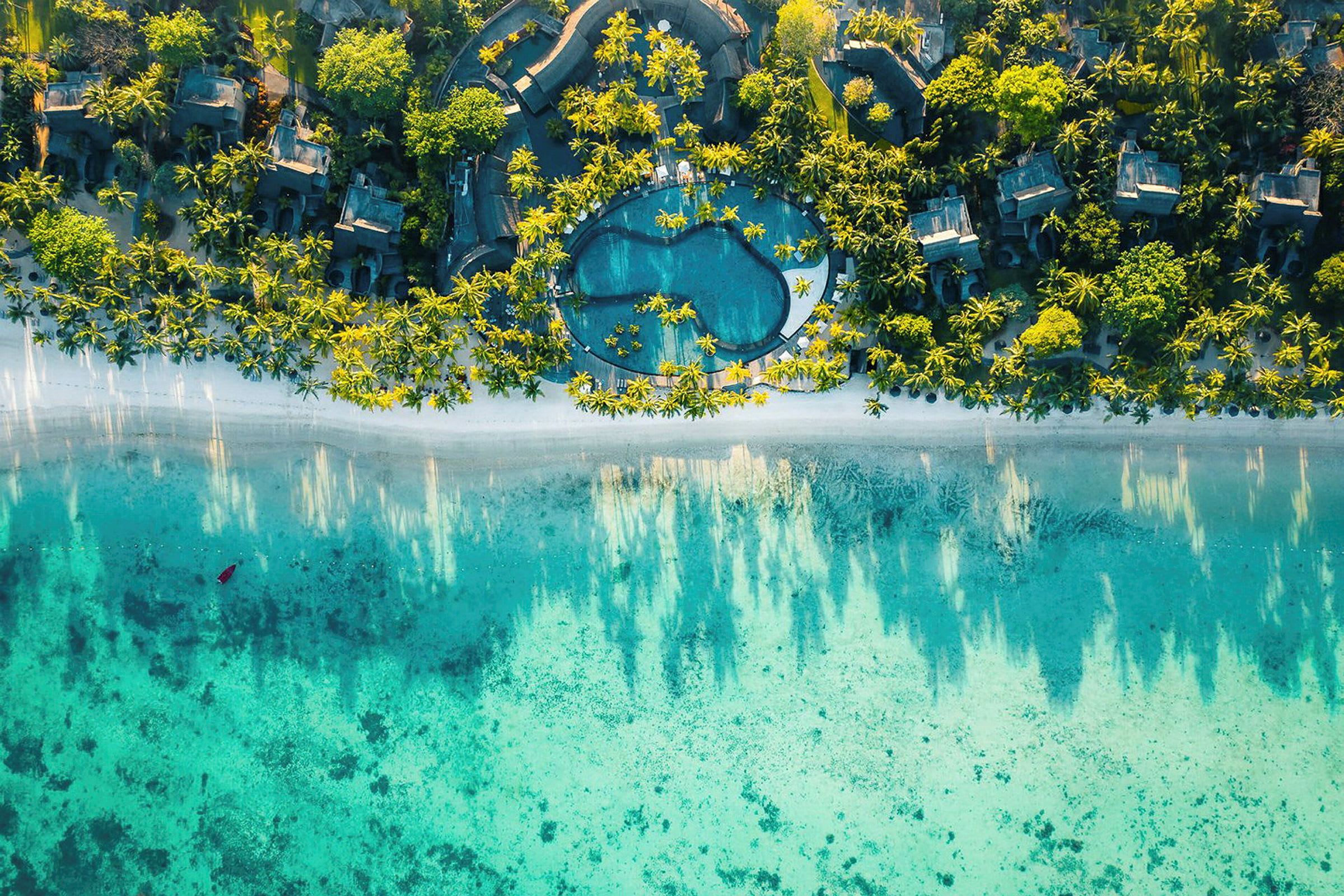 Flygbild över tropisk resort med pool och strand. (AI-genererad text)