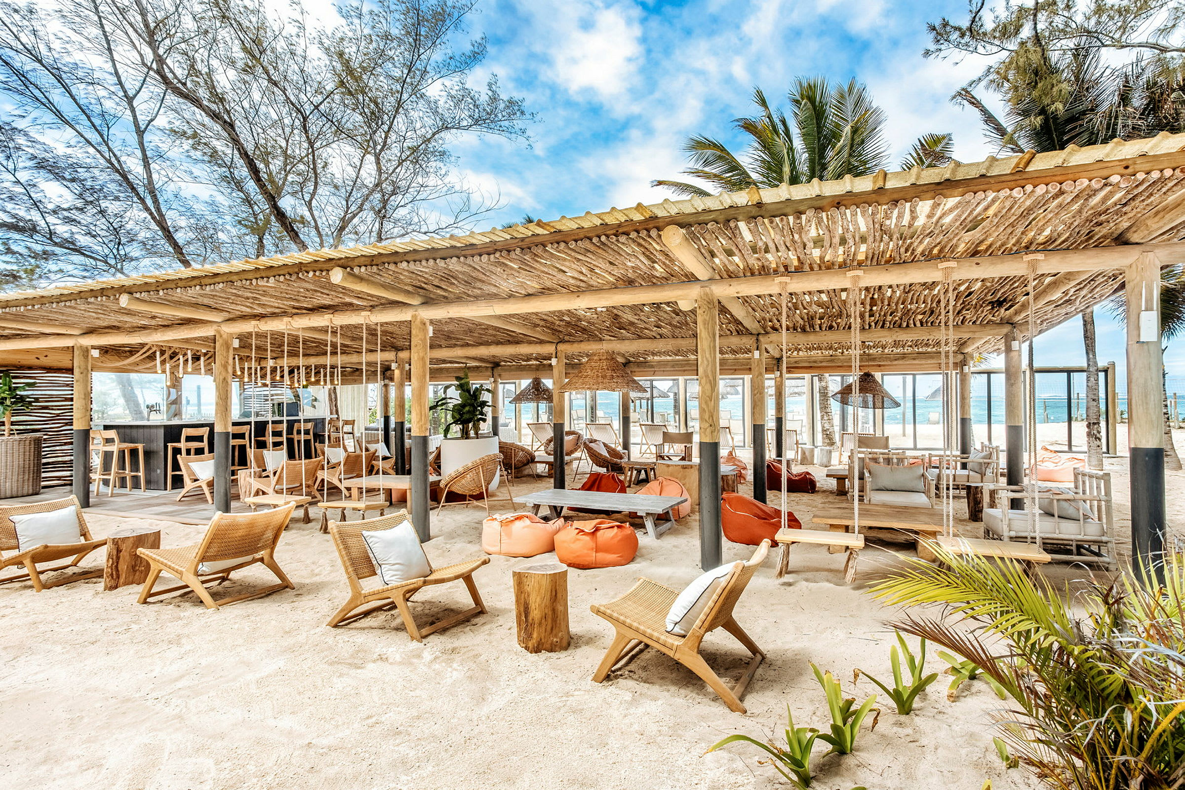 Strandbar med sittmöbler och hängmattor under träskärmtak. (AI-genererad text)