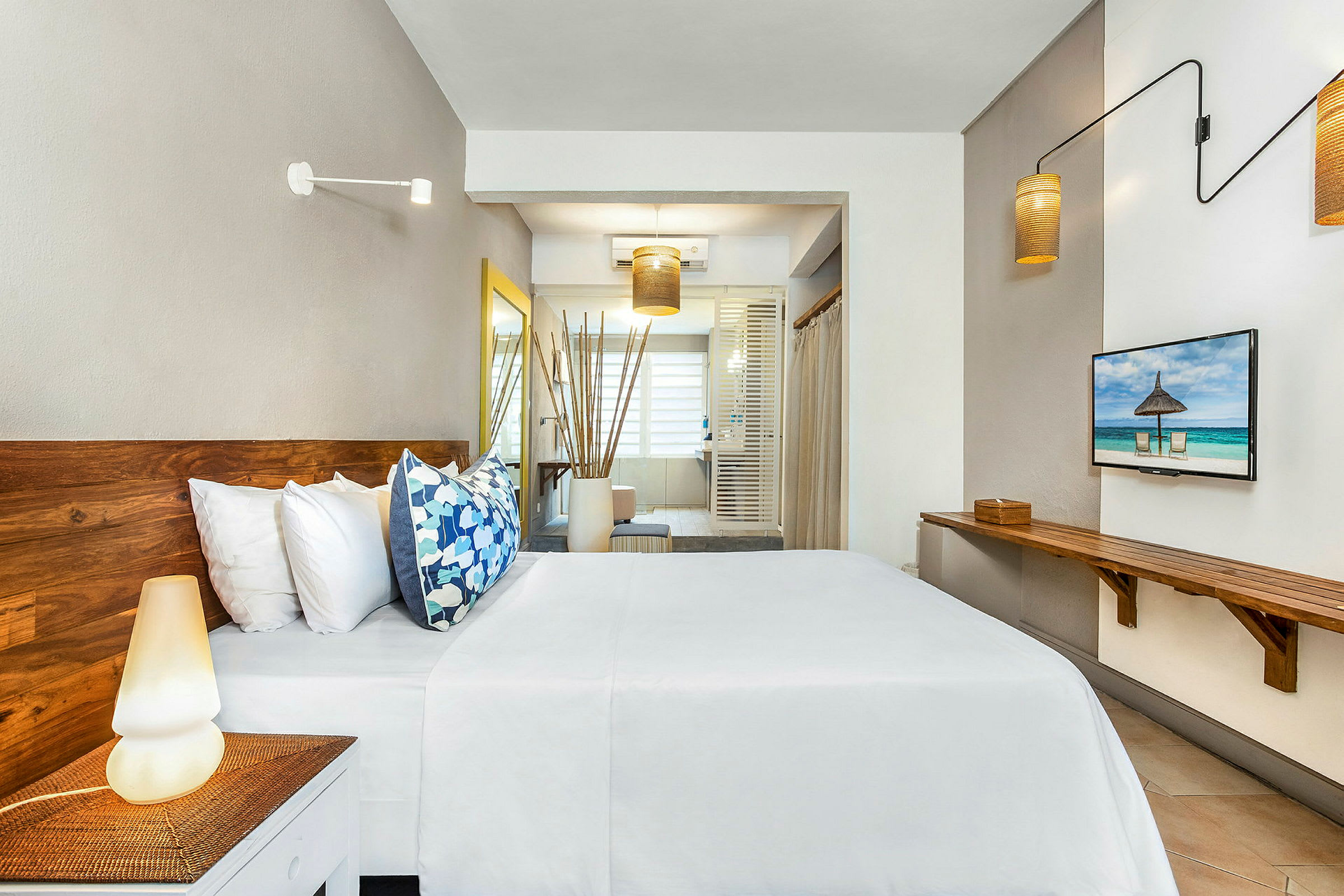 Bild av ett modernt hotellrum med trämöbler, säng med vita lakan och färgglada kuddar, och ett stort fönster i bakgrunden. (AI-genererad text)